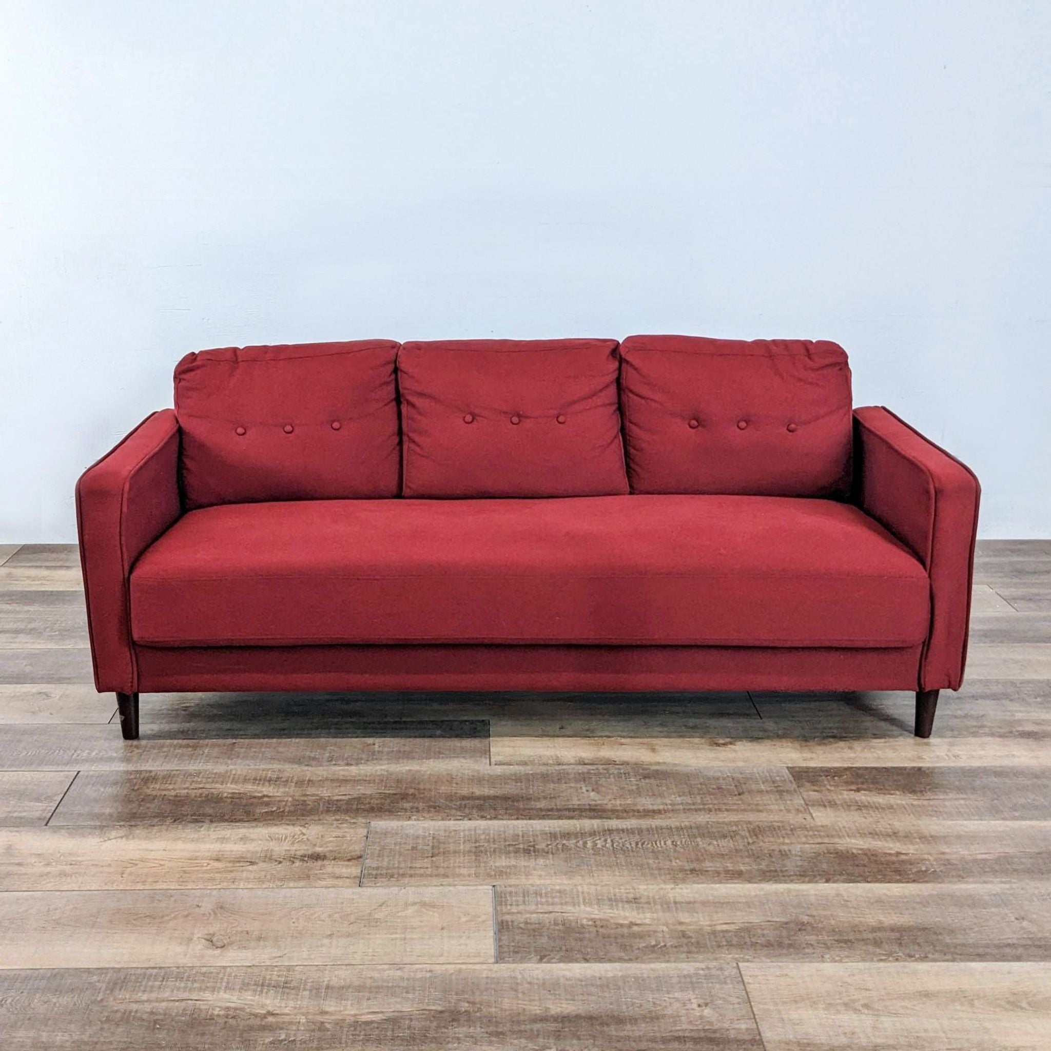 1. Zinus Mikhail Mid-Century 3-seat Sofa with red upholstery, button tufting, and tapered wood legs, on a wood floor.