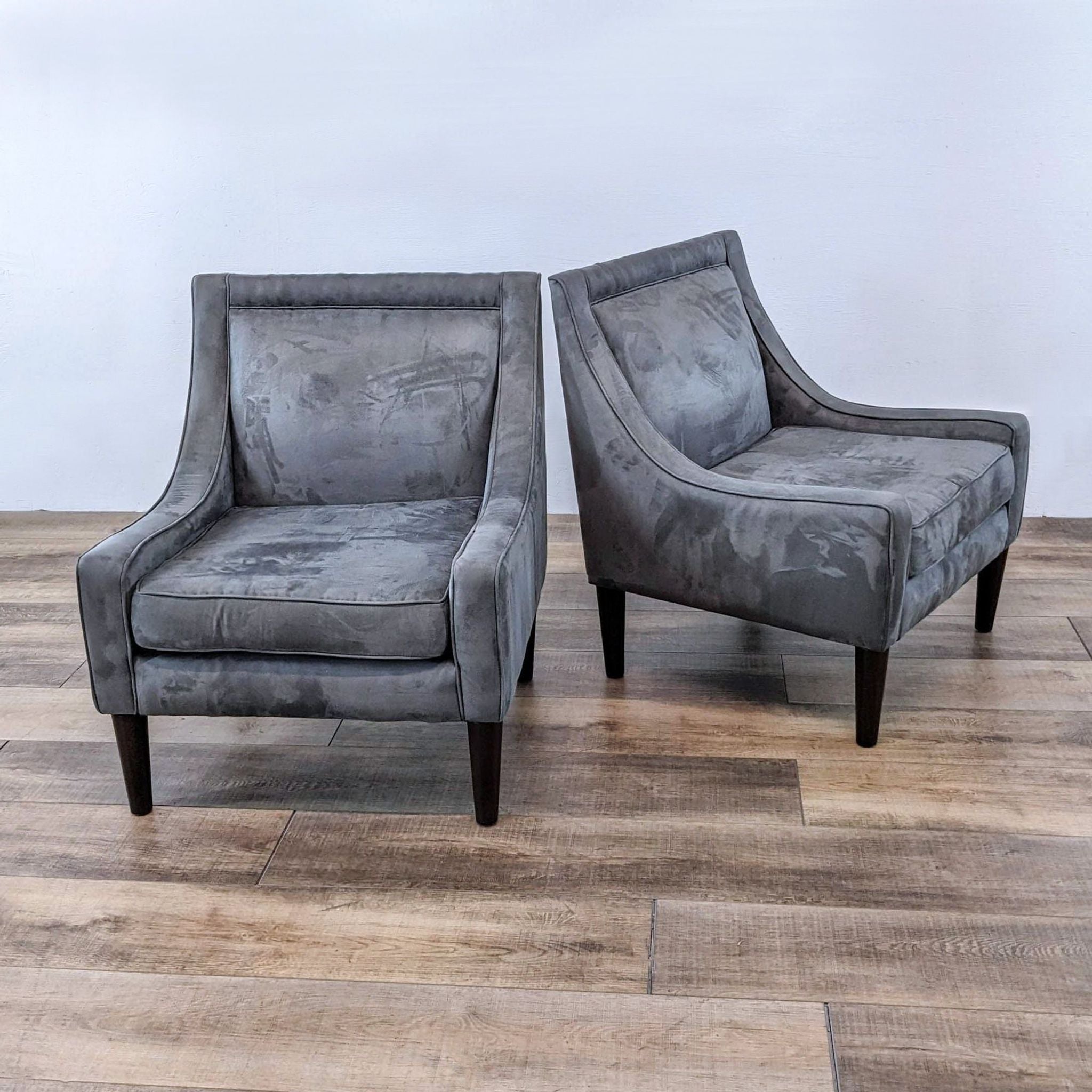 Skyline Furniture armchairs with plush seating and sloped narrow arms, tapered wood legs on a wooden floor.