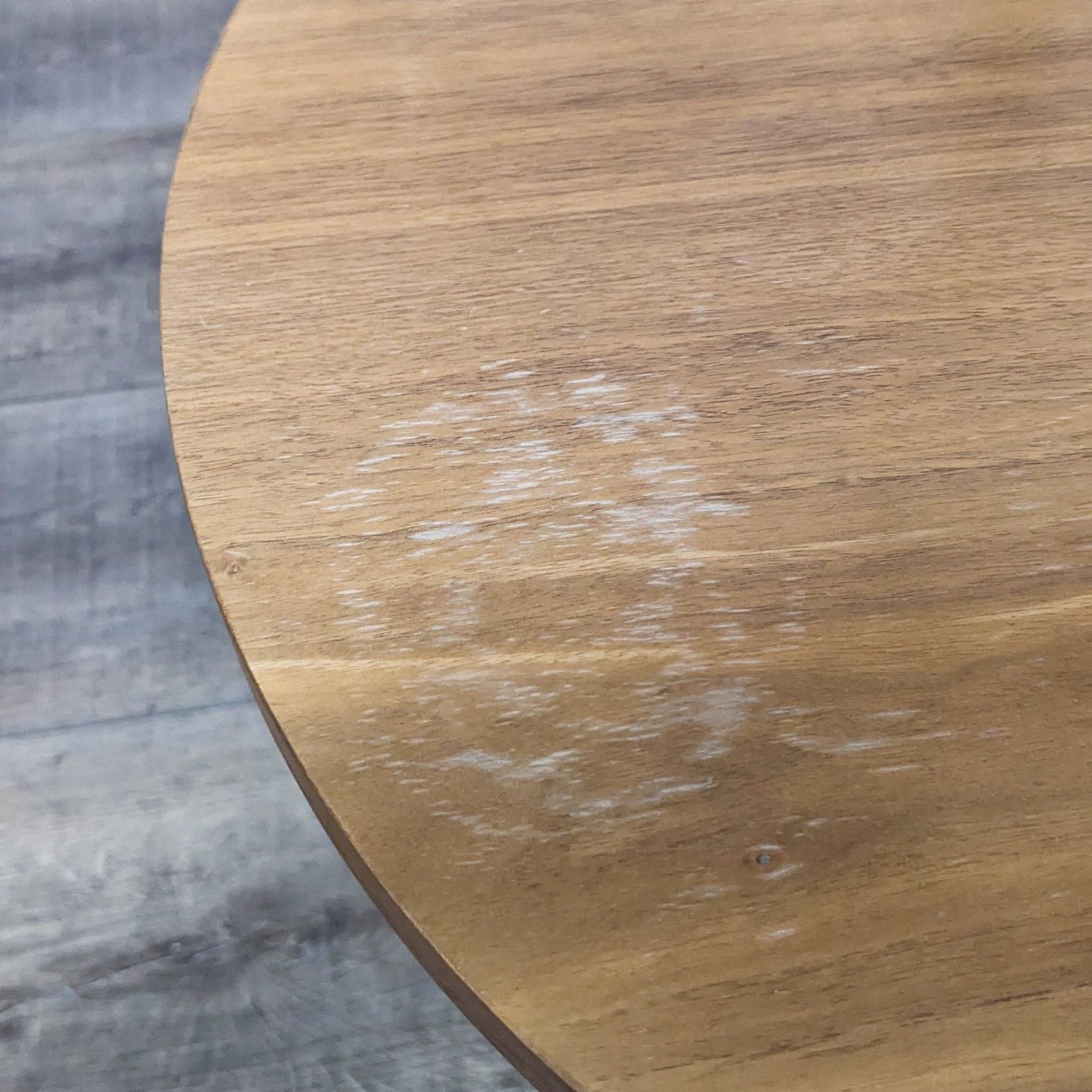 Close-up of a circular wooden shelf with a visible water stain on its surface.