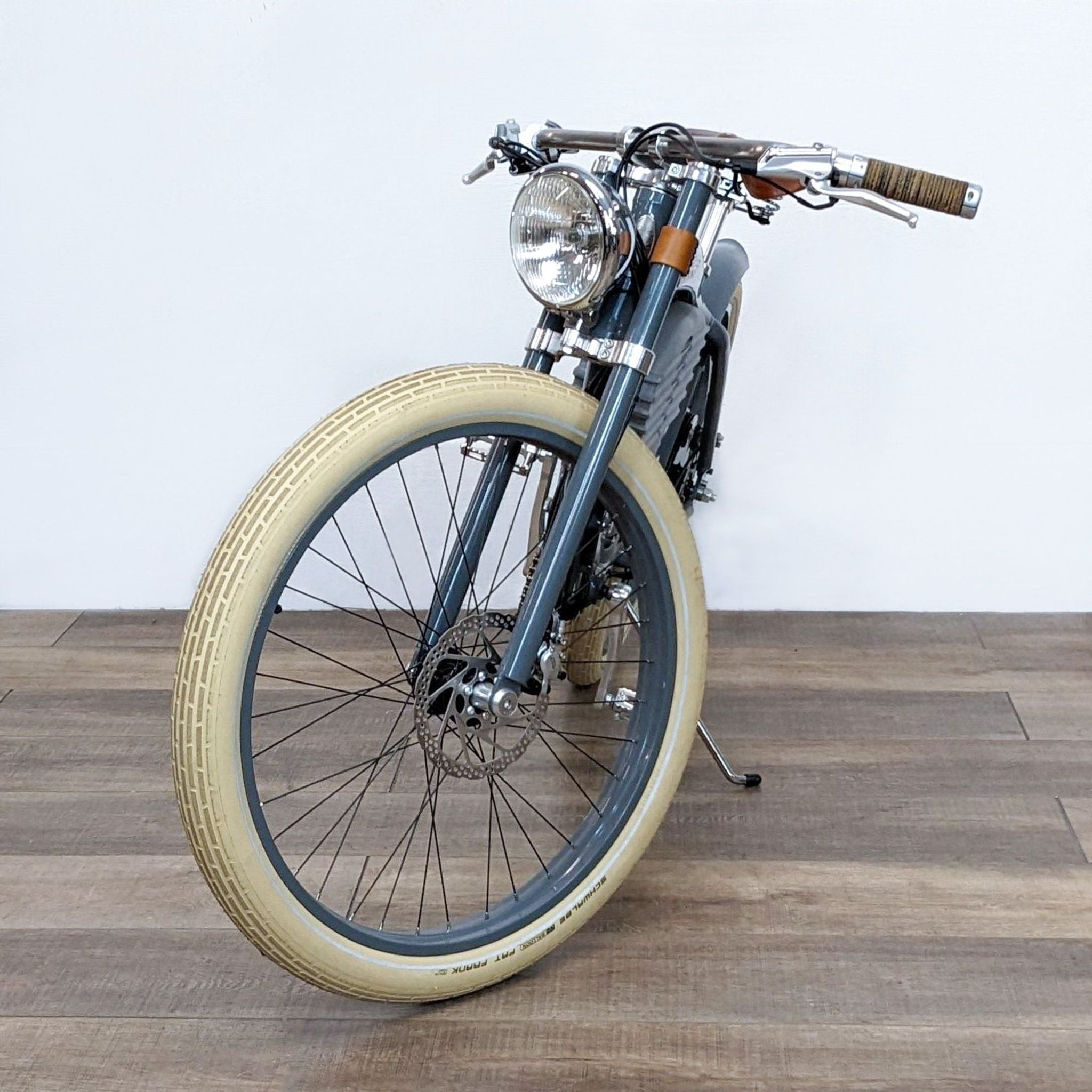 2. Front view of a Vintage Electric bicycle highlighting the headlight, brown hand grips, and the large front cream-colored wheel.