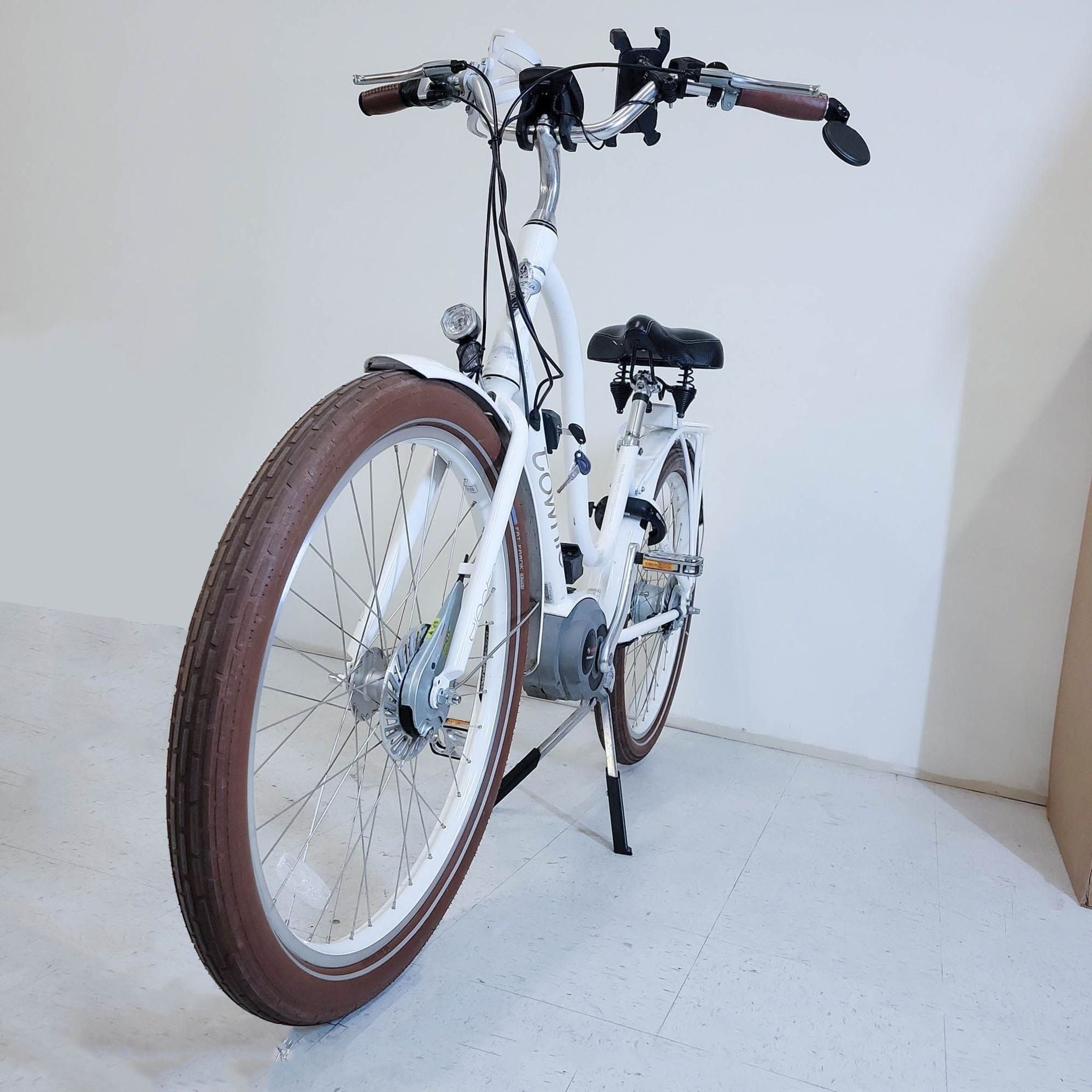 White Electra Townie Go motorized e-bike with ergonomic design and comfortable seat, positioned indoors.