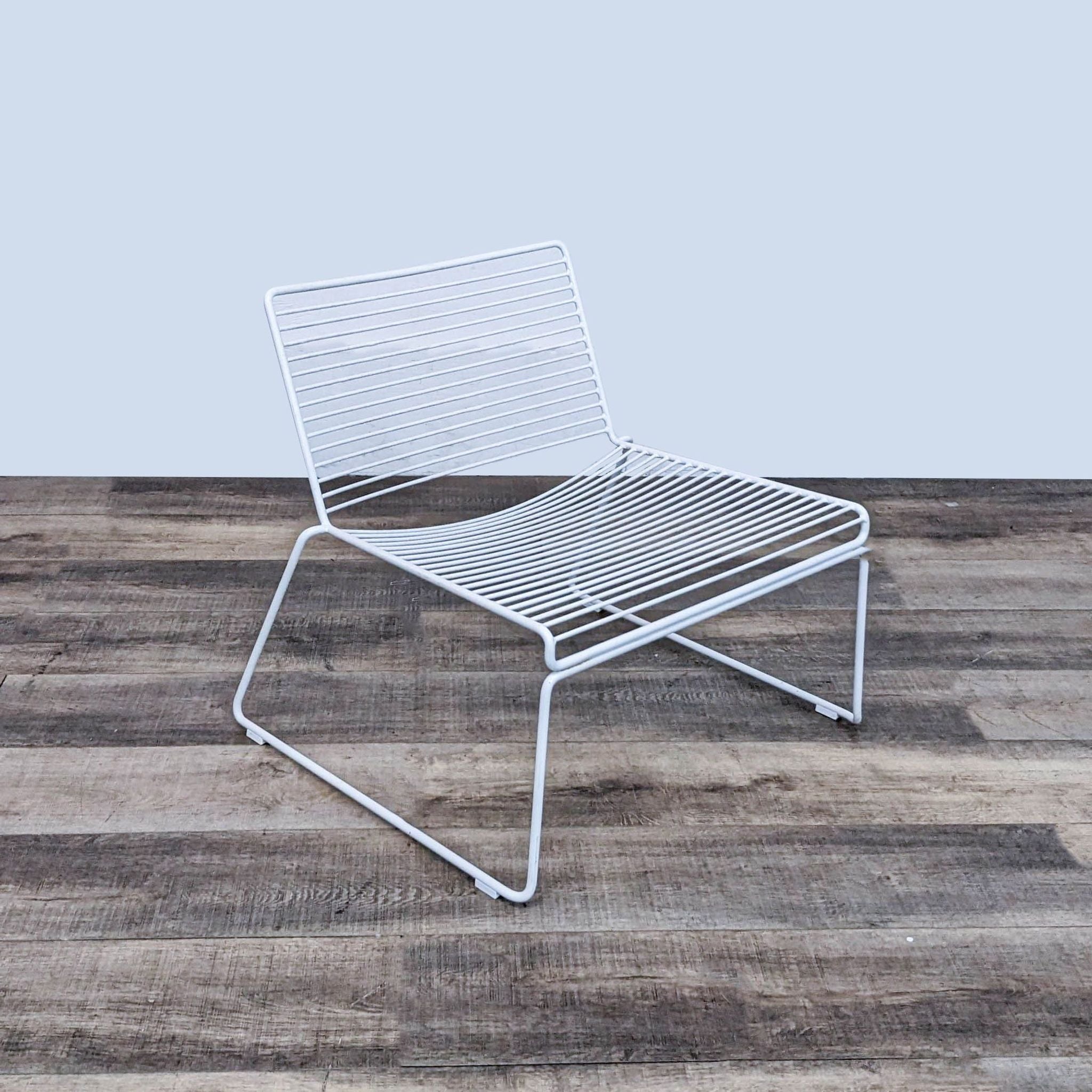 White modern Hee Chair by Design Within Reach featuring a wide seat, low height, and powder-coated steel frame on wood flooring.