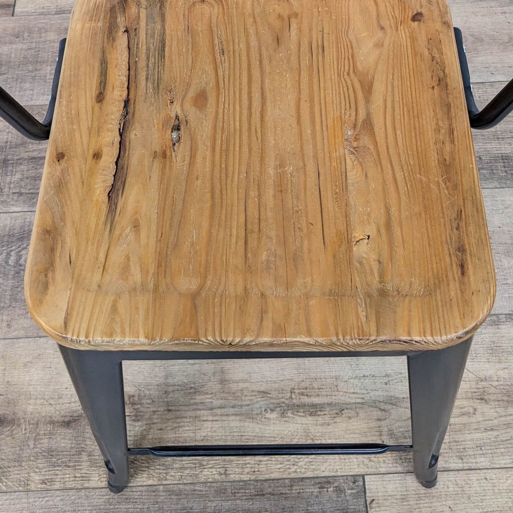 Top view of a CB2 stool showcasing its solid wood seat and the black metal frame structure.