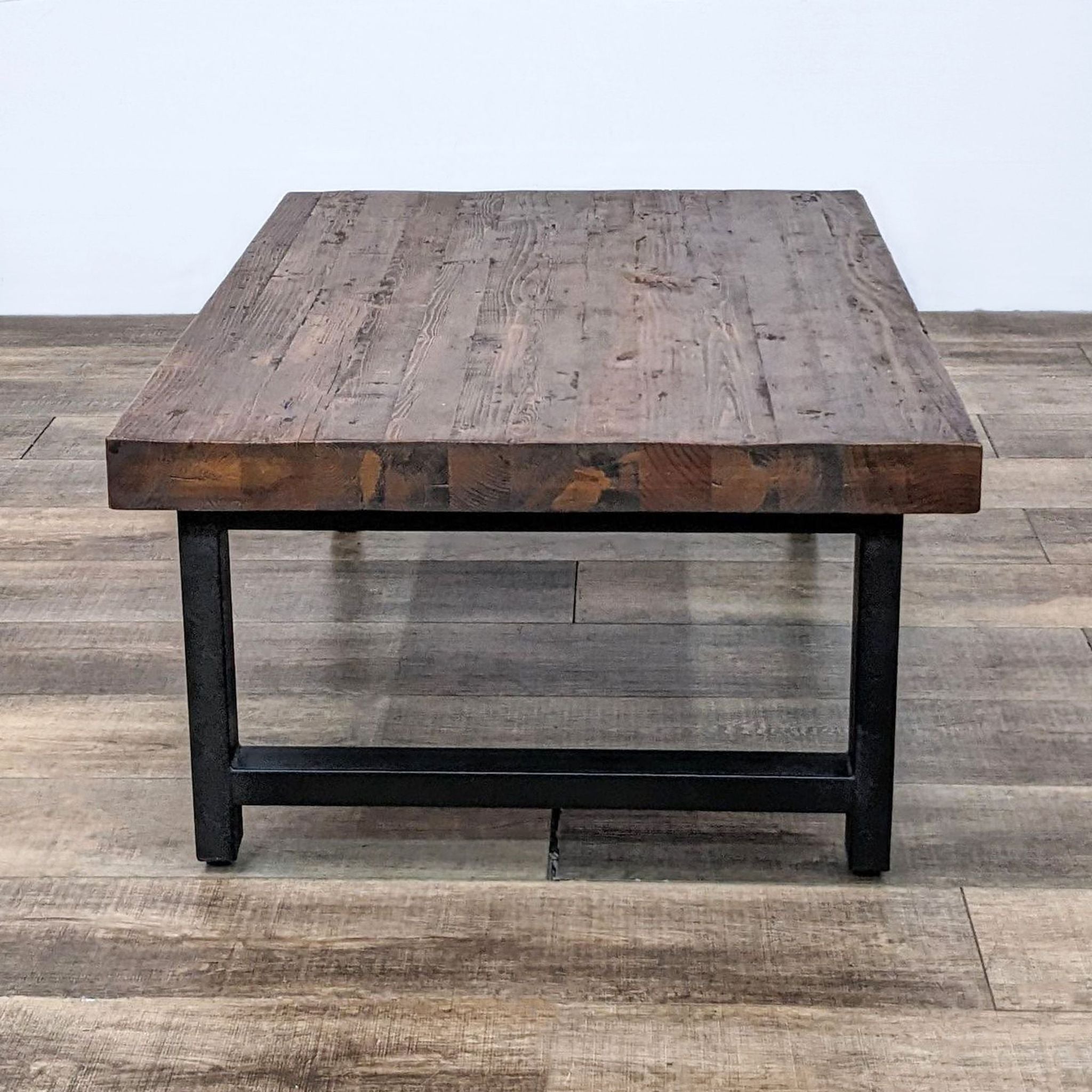 Rustic Reperch brand coffee table featuring distressed pine top, oil stains, and black legs with adjustable levelers for stability.