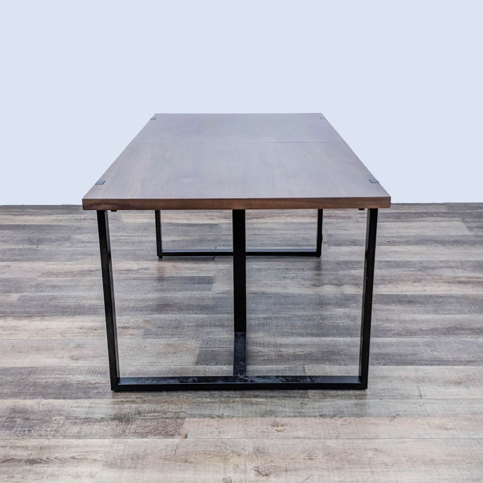 Article brand modern wood finish conference table with a black metal frame on a wooden floor.