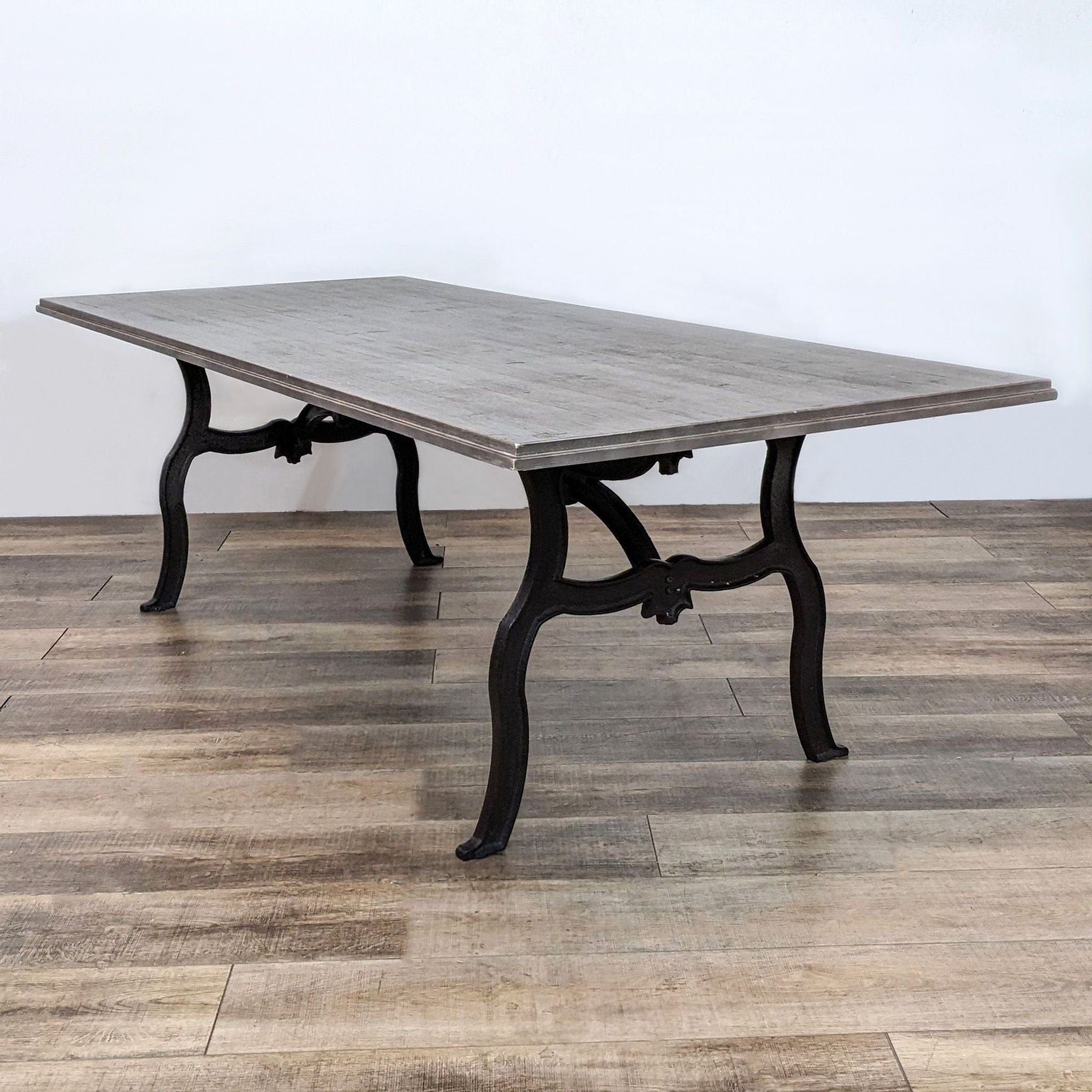 Alt text 2: Rectangular Reperch dining table featuring a rich distressed top and ornate scrolled black legs from a side angle.