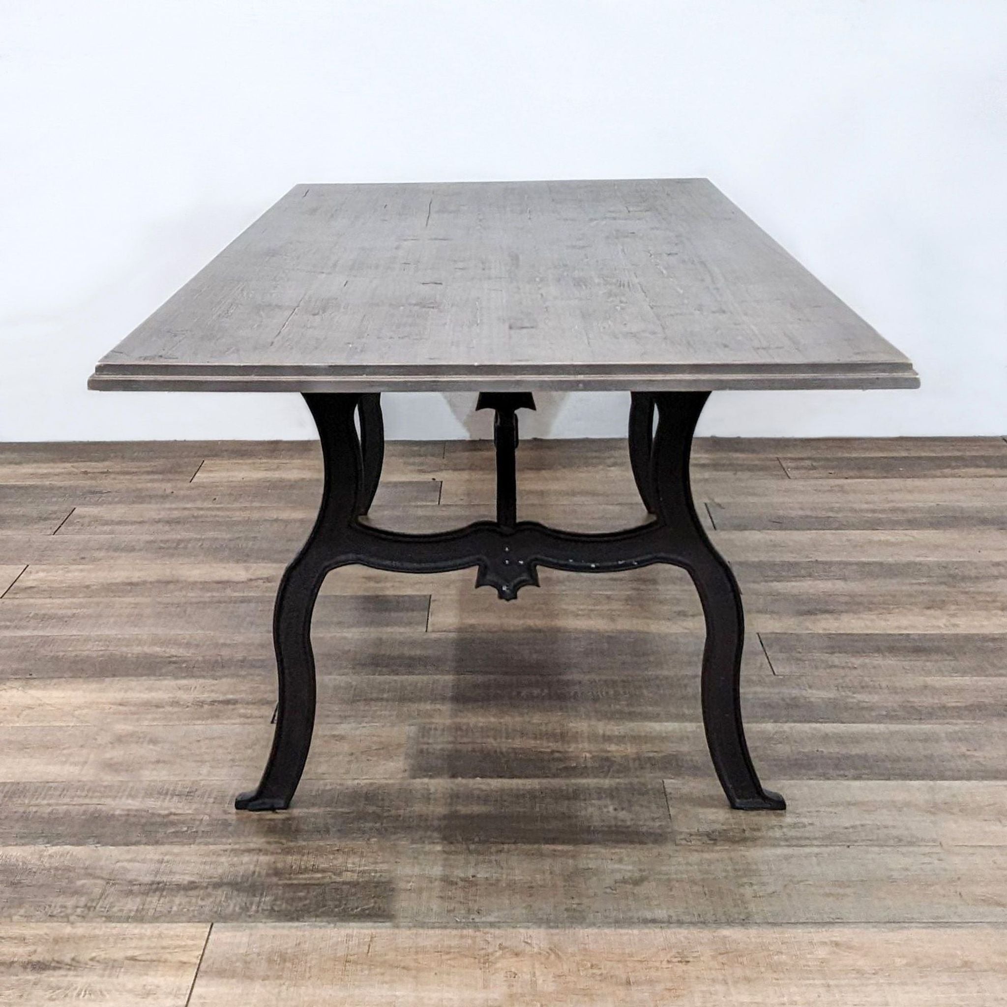 Reperch-brand dining table with scrolled trestle base in black finish and a rectangular distressed fir wood tabletop.