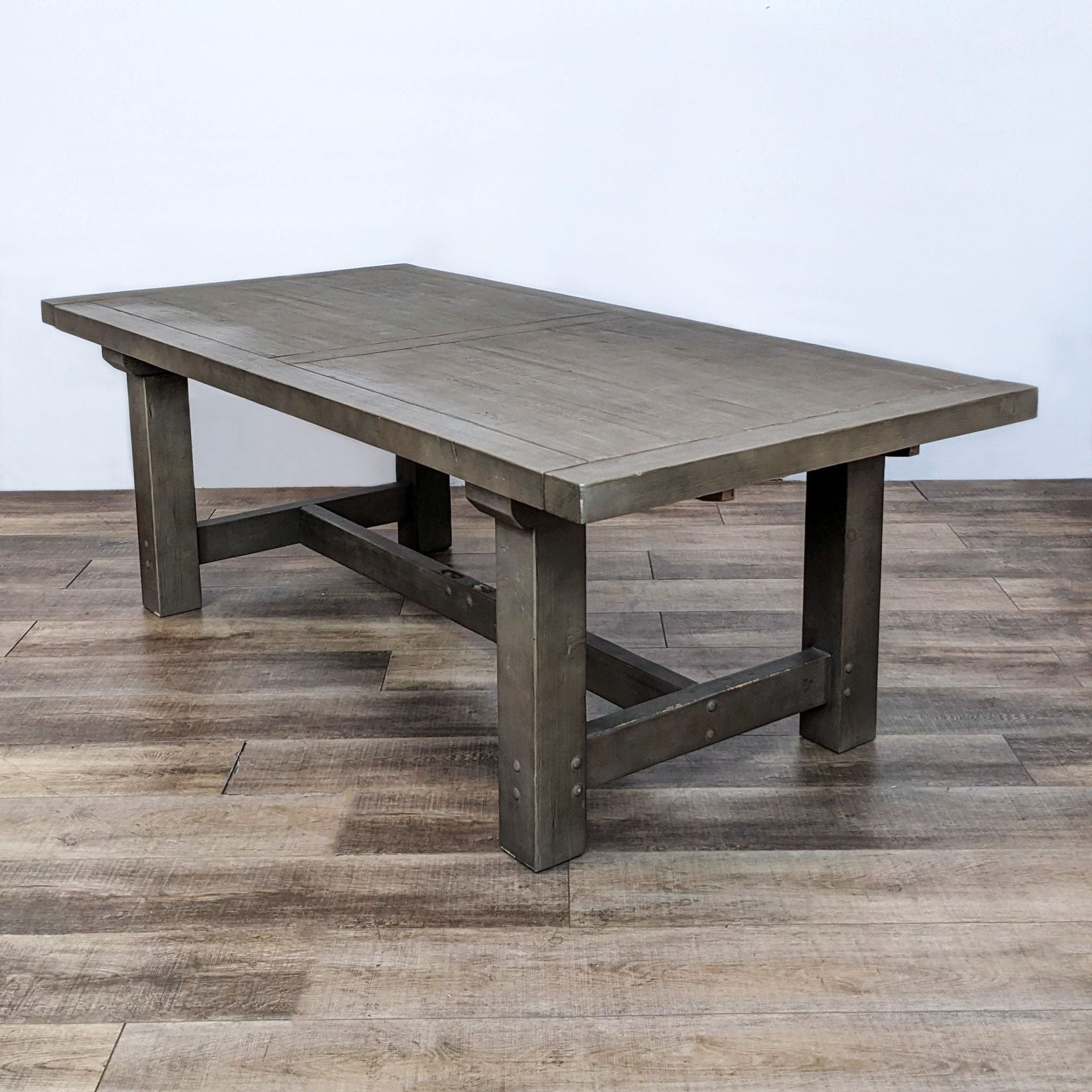 Reperch farmhouse style dining table made of wood and veneer with a trestle base, shown on a wooden floor.