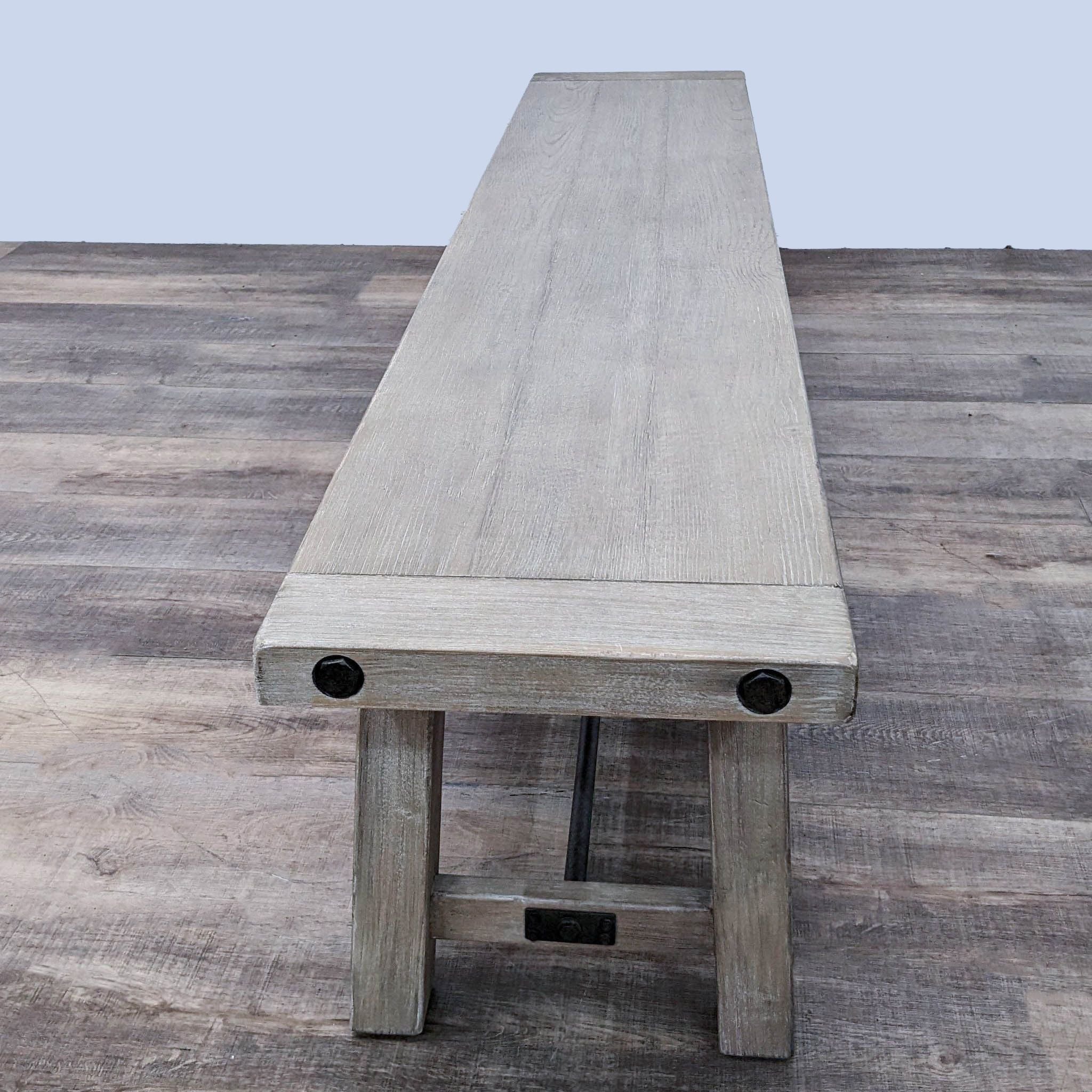 Solid wood rustic dining bench with metal accents on a wooden floor, Pottery Barn.