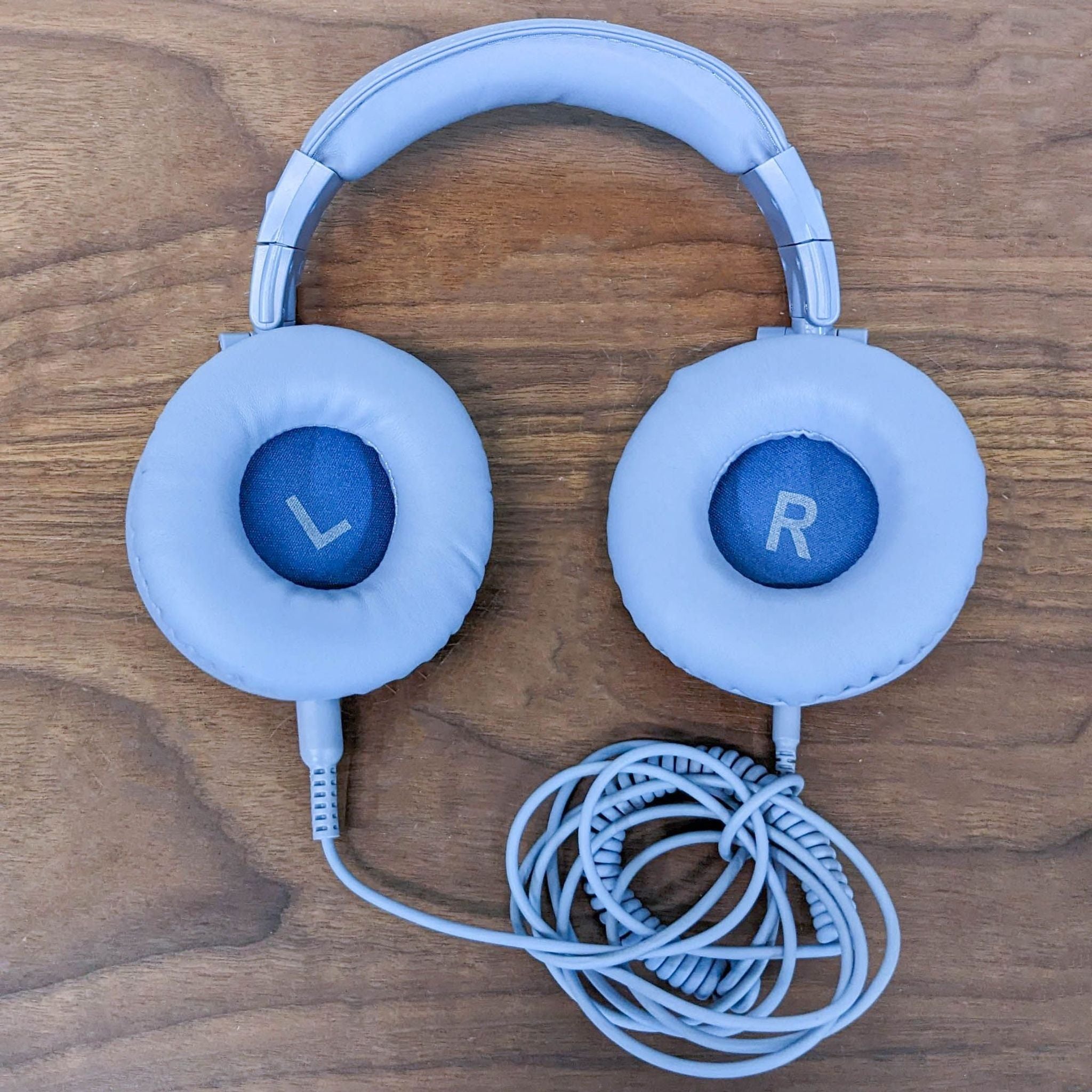 OneOdio over-ear headphones in white with "L" and "R" indicators, coiled cable on a wooden surface.