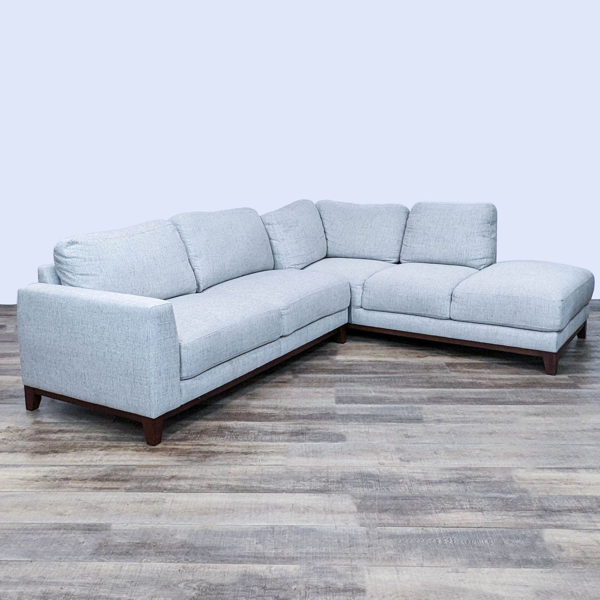 112-inch Living Spaces sectional in a neutral tone, featuring soft cushions and dark wood frame, with a chaise extension.