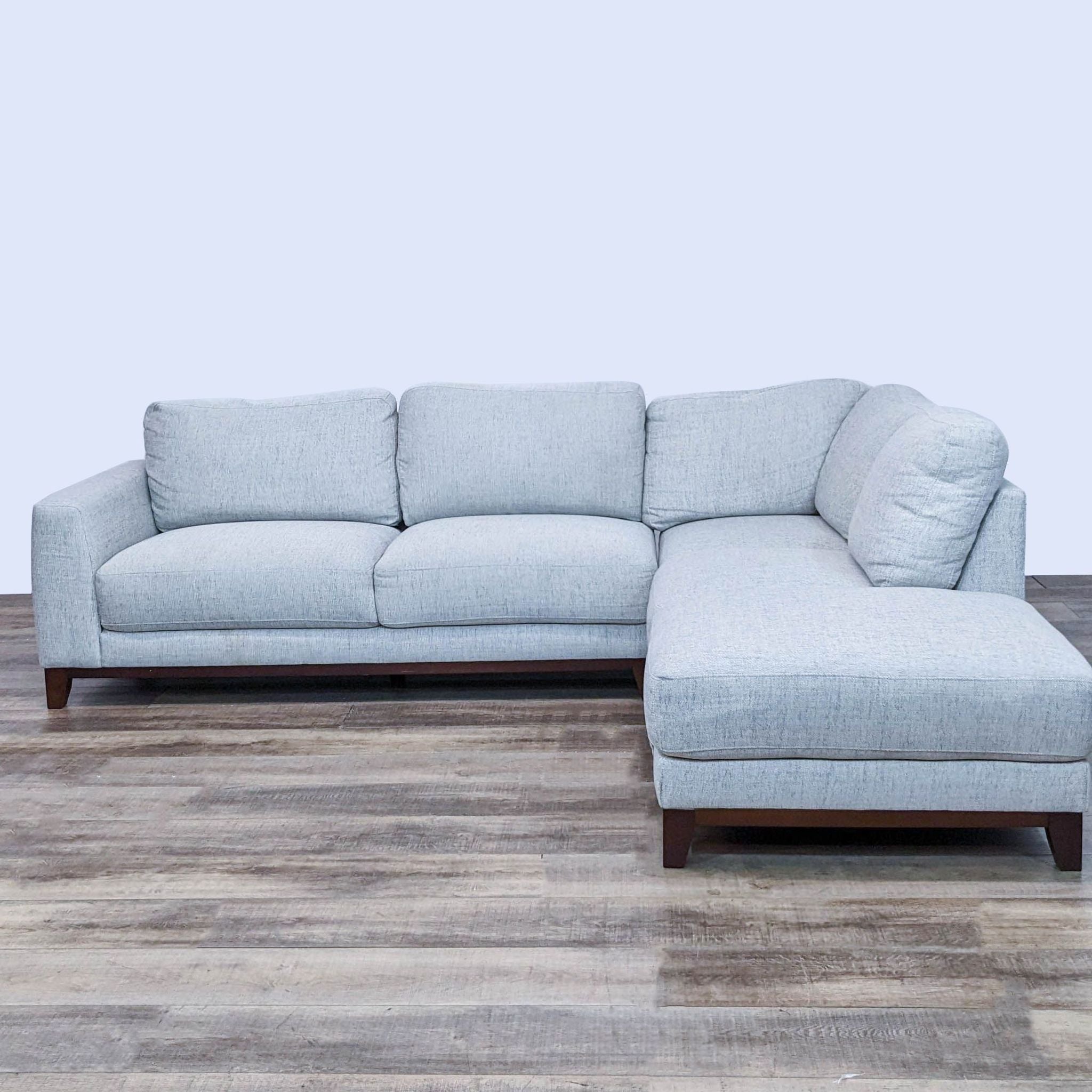 Neutral-colored 112" sectional sofa by Living Spaces, with plush back cushions on a dark frame, and a chaise on a wooden floor.