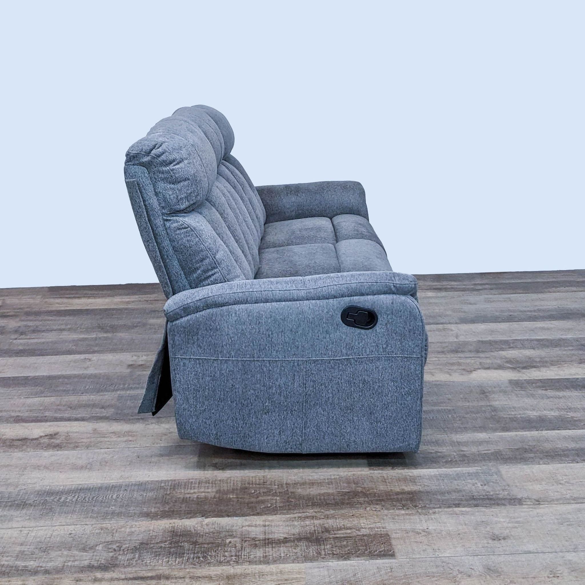 Side view of a gray Living Spaces 3-seat high back dual reclining sofa with pillow top arms.