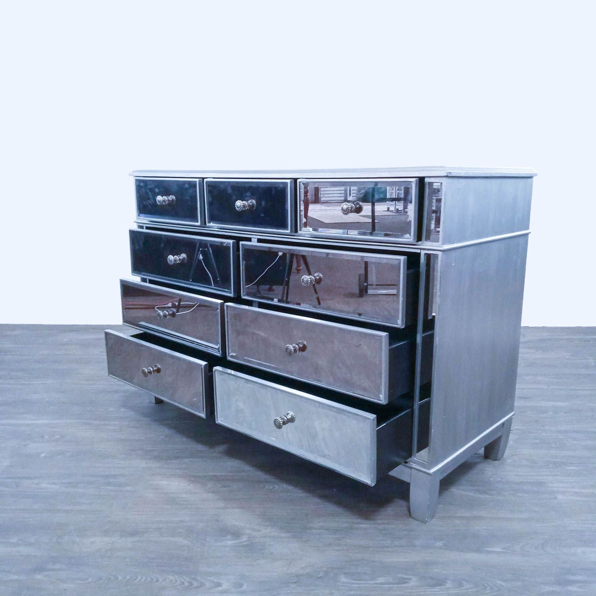 Silver-finished wood framed Hayworth dresser with nine mirrored drawers, angled view showcasing open top drawers.