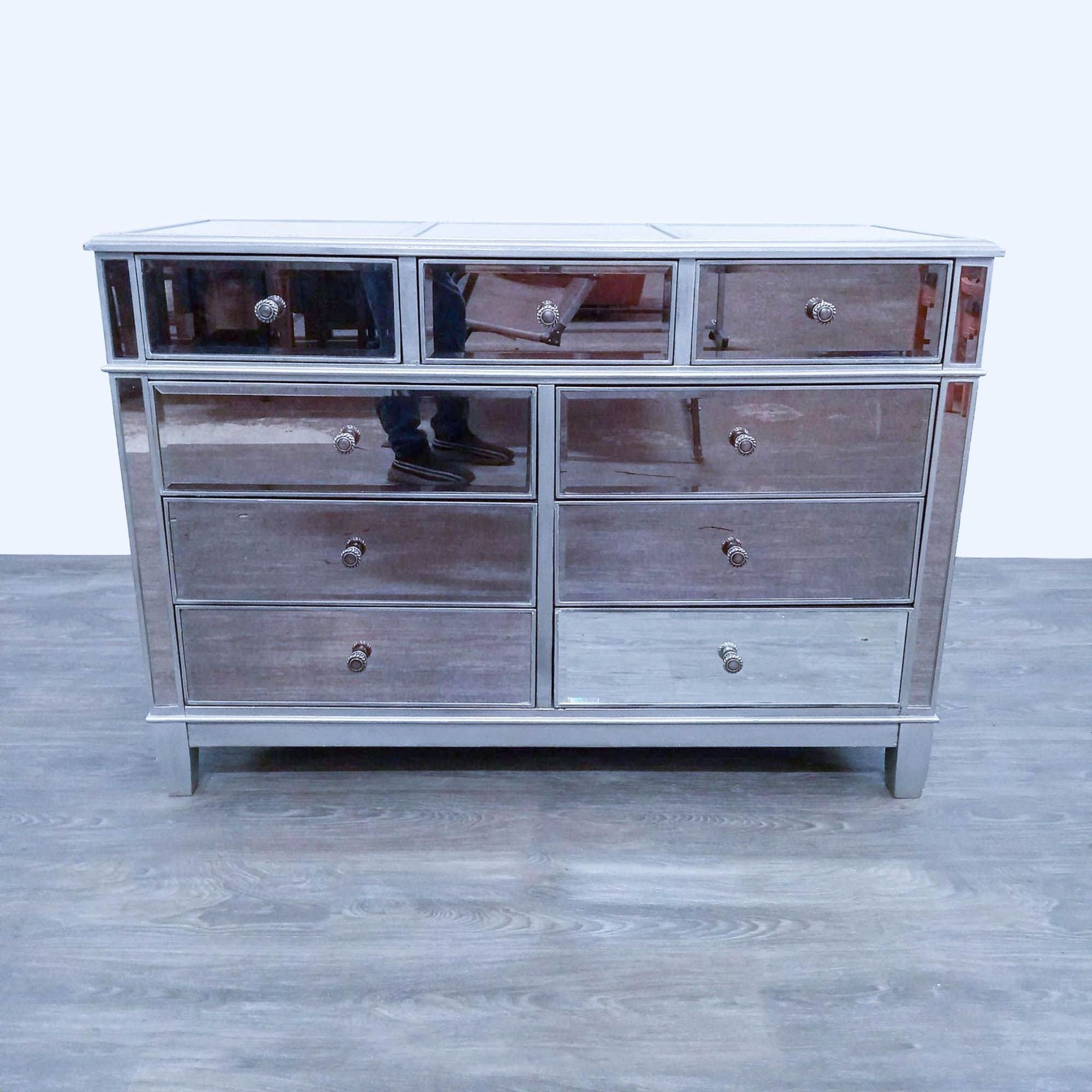 Hayworth dresser by Pier 1 Imports with mirrored front drawers and silver wood frame, viewed frontally on a grey floor.