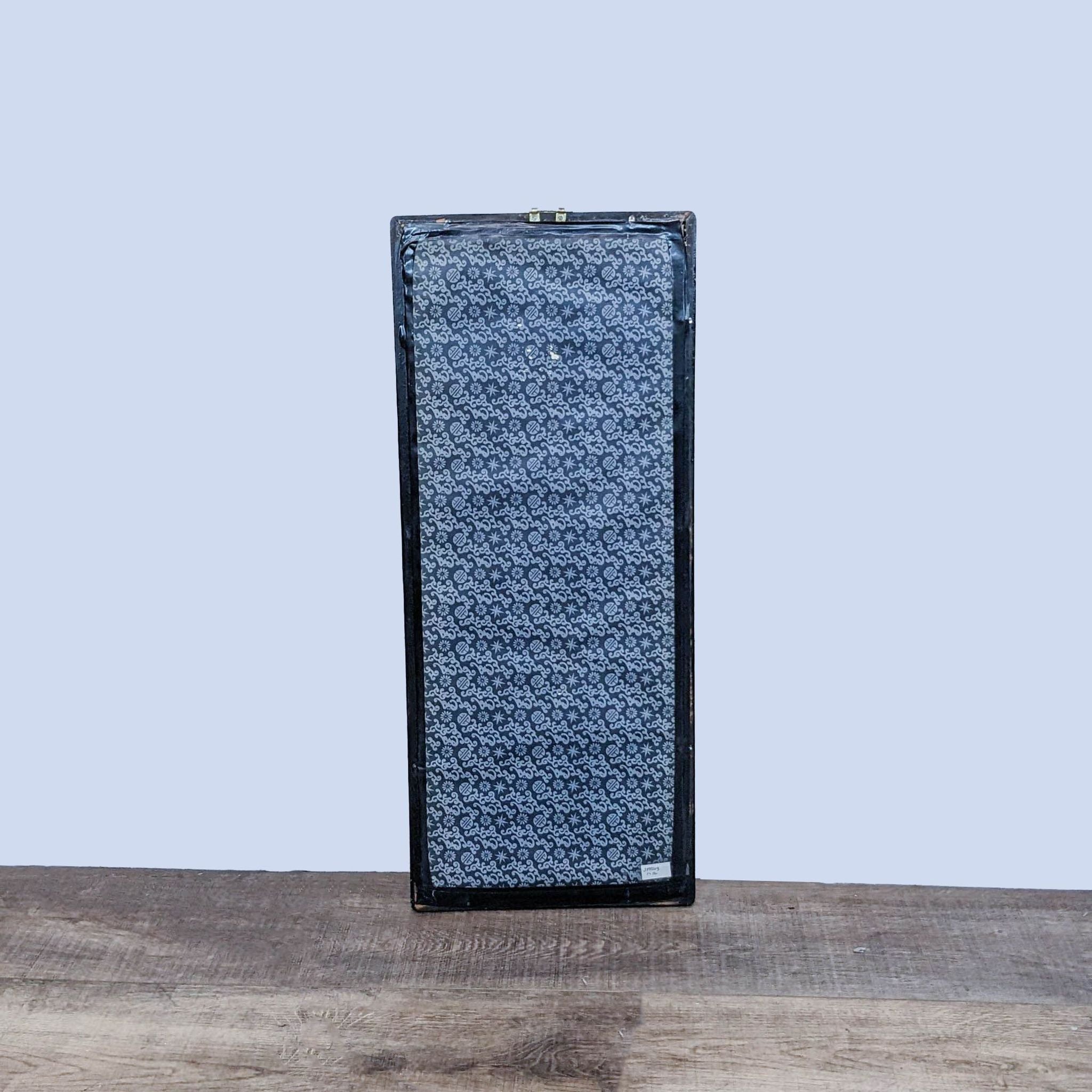 Rectangular floral-patterned clutch purse by Reperch on a wooden surface against a light blue background.
