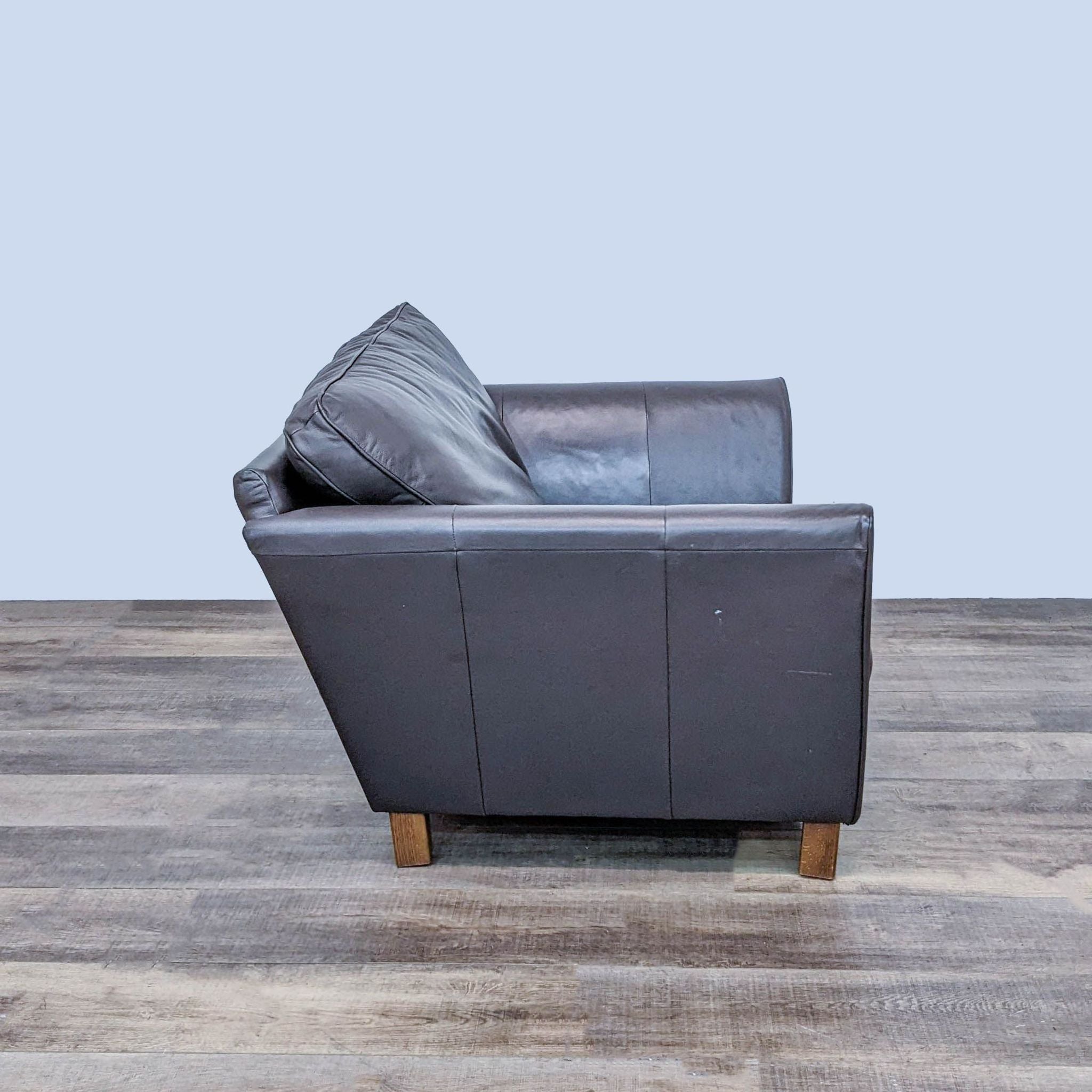 Side view of a leather lounge chair by Marks & Spencer, displaying wooden feet and design.