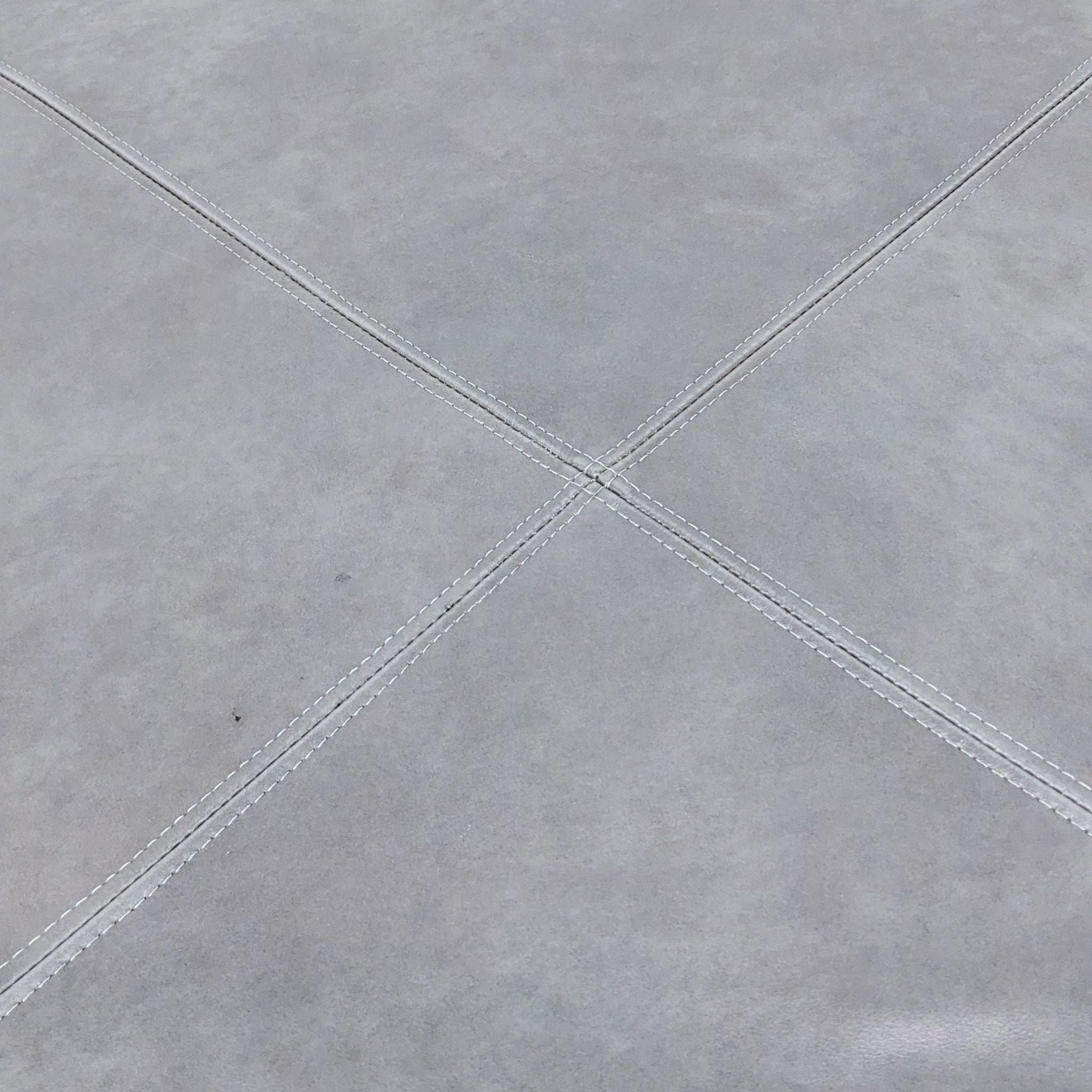 Close-up of gray leather surface with stitched detailing.