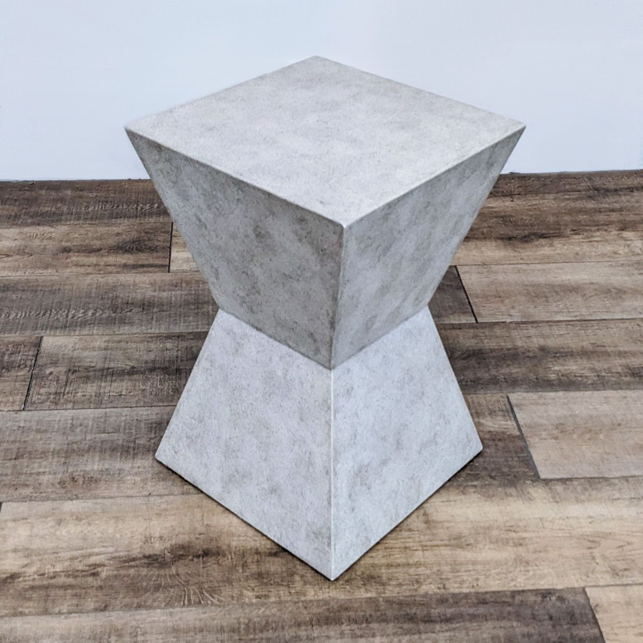 Reperch brand faux concrete end table with angular design on a wooden floor.