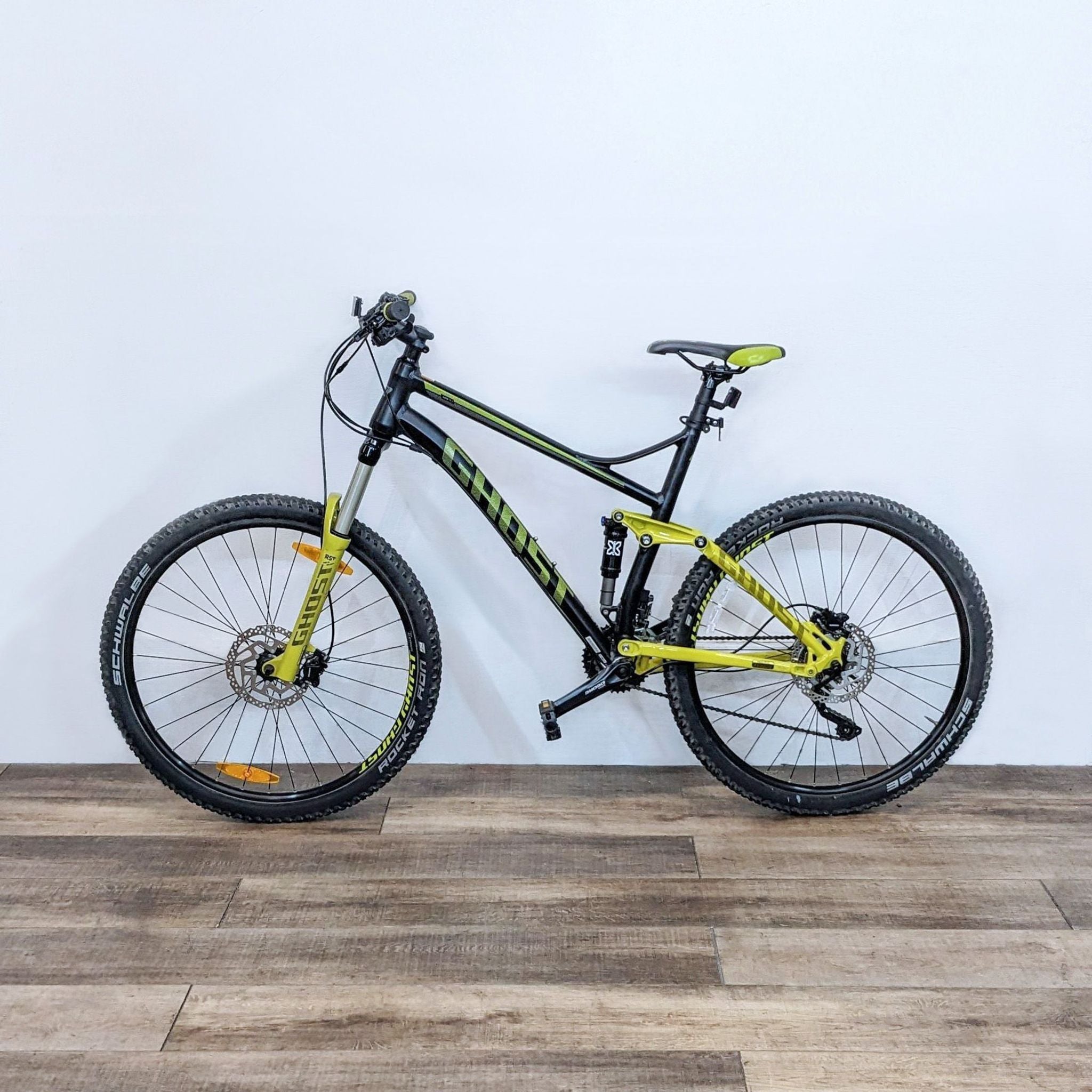 REI full-suspension mountain bike in black and yellow, designed for rugged terrain with visible safety labels.