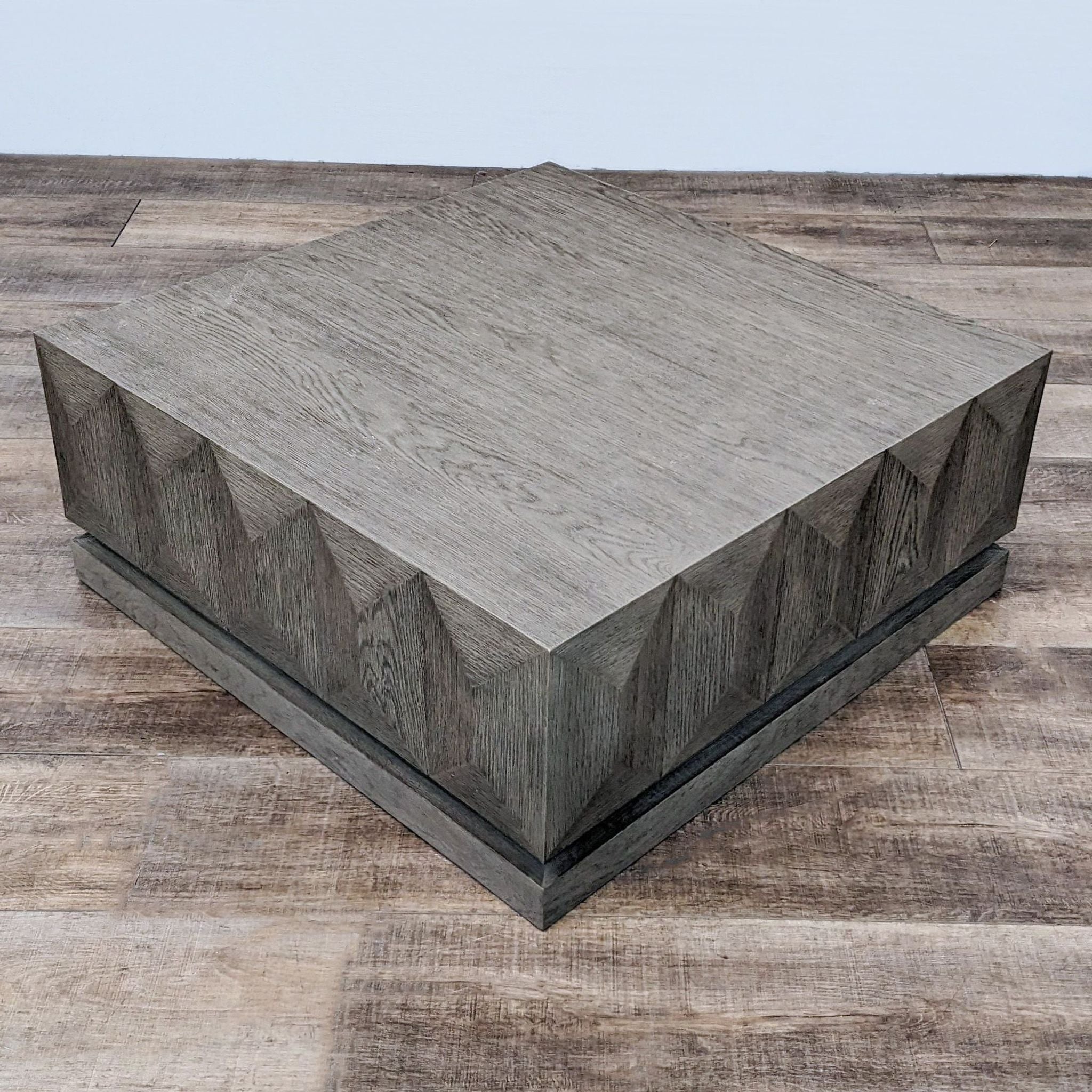 Reperch block style gray stained coffee table with geometric base design on wooden floor.