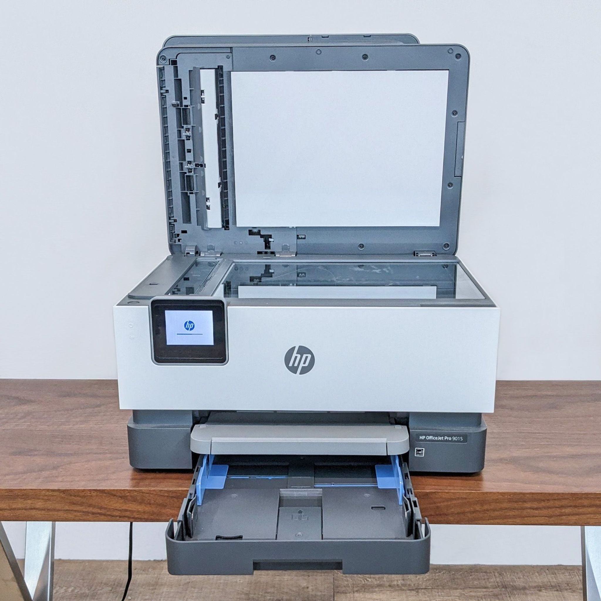 HP all-in-one printer on a desk with the scanning lid open and paper tray extended, ideal for a home office.