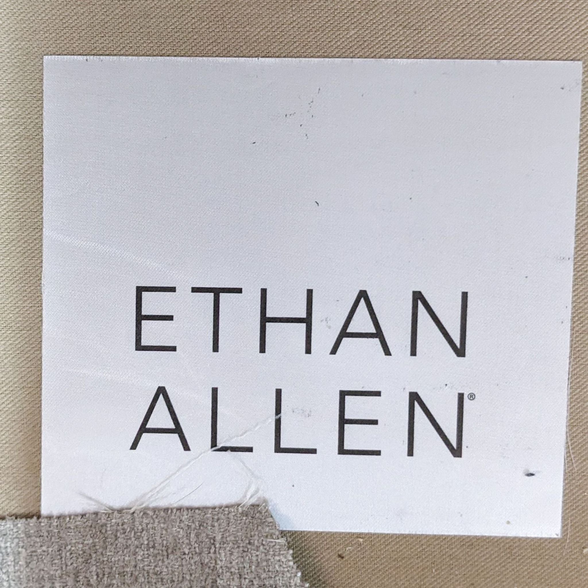 Label showing "ETHAN ALLEN" brand logo on a white background with frayed edges at bottom left.
