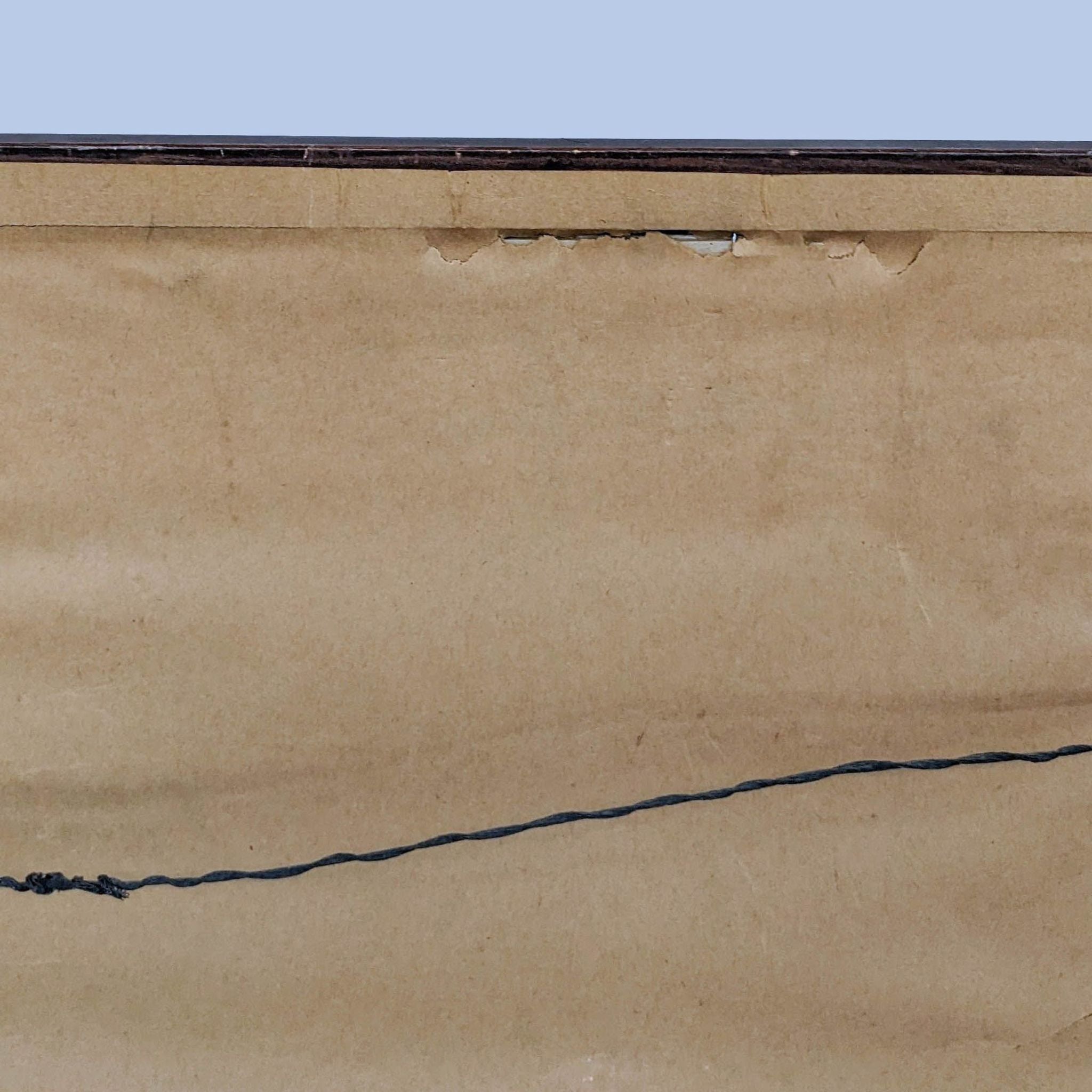 Back of a framed artwork showing brown paper backing and black wire hanger.