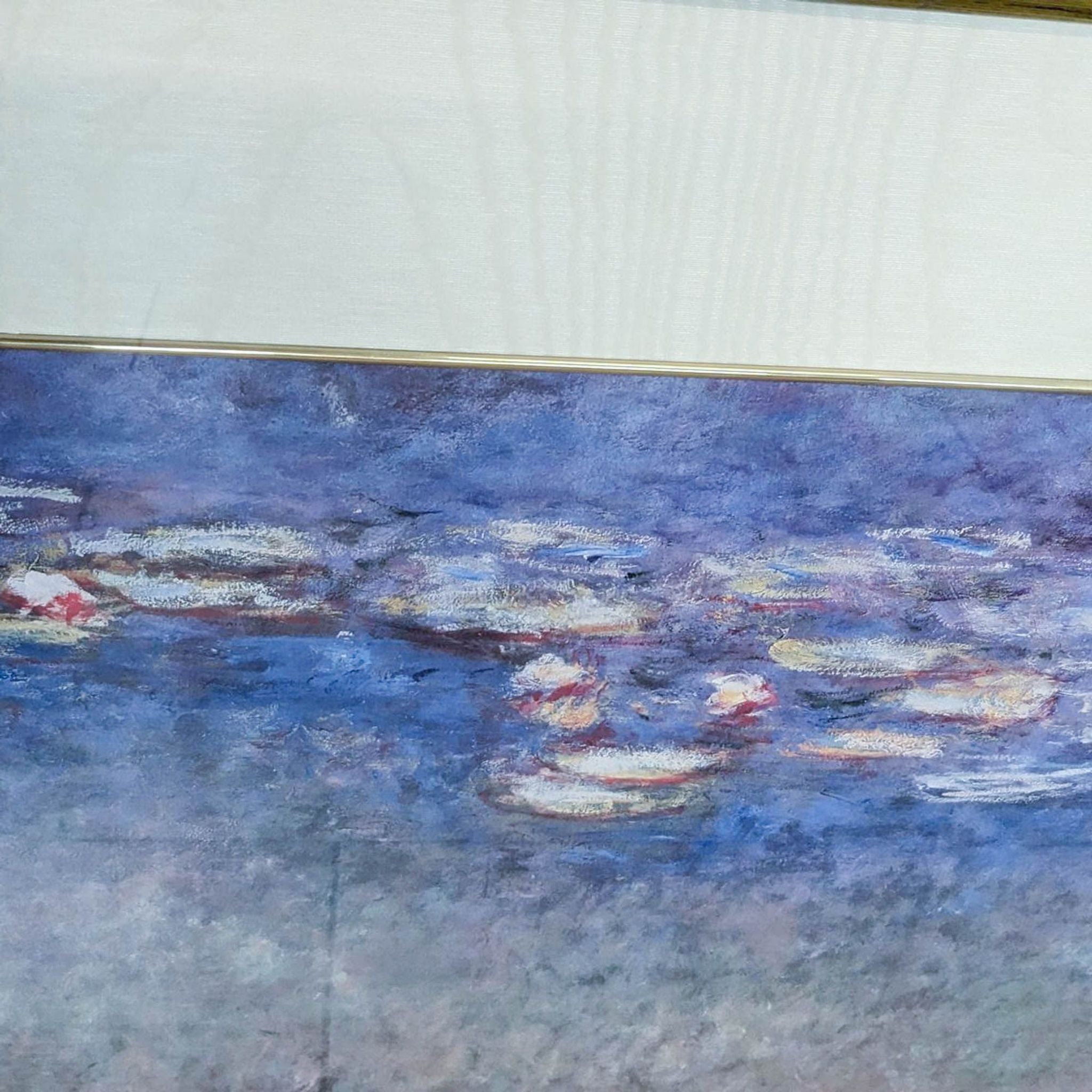Alt text 2: Back view of a framed Monet "Water Lilies" lithograph showing label and hanging wire, against a woodgrain floor.