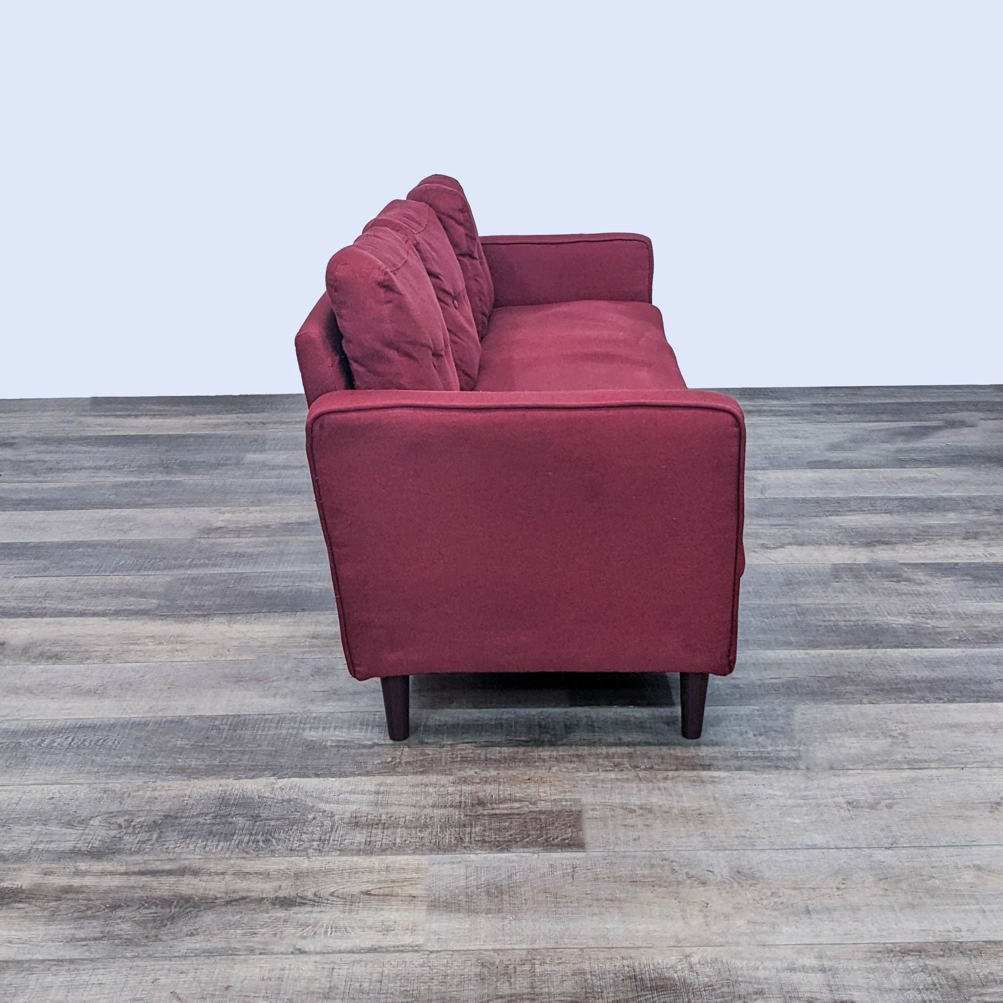 Side view of a Zinus brand 3-seat red button-back bench sofa with narrow arms and wooden legs on a wooden floor.