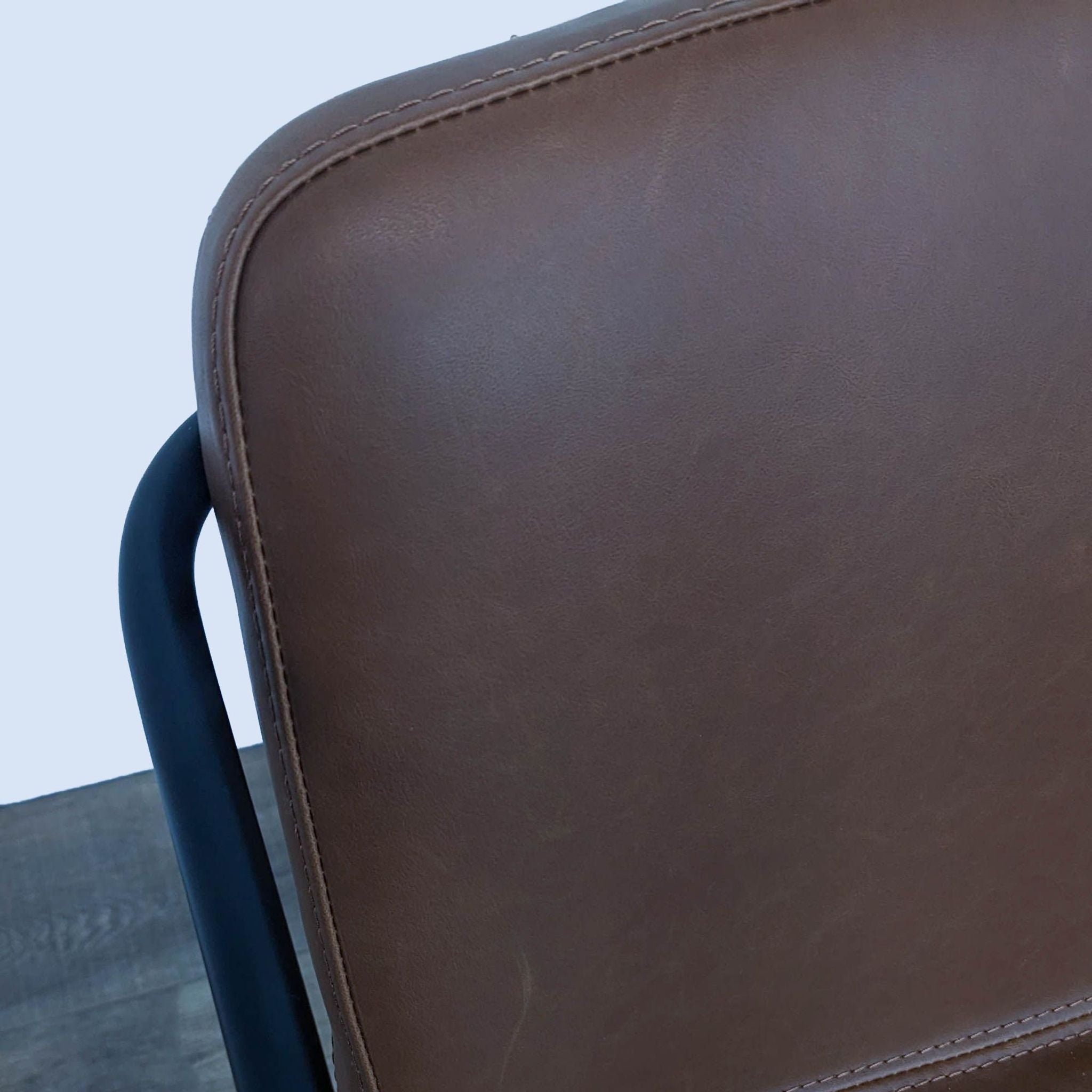 Close-up of a Room & Board brown leather-look counter stool showcasing the quality of the material.