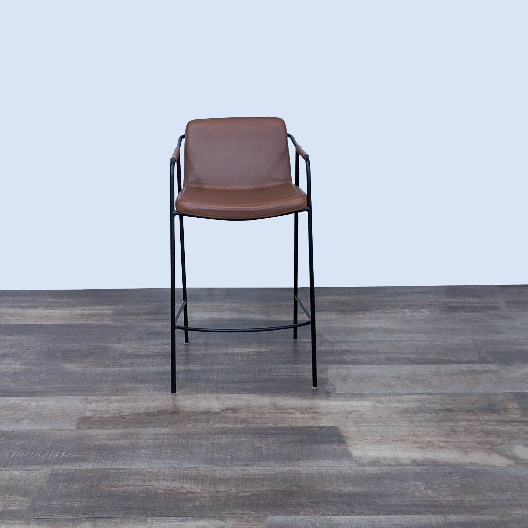 Room & Board minimalist brown leather-look counter stool with a black steel frame on a wooden floor.