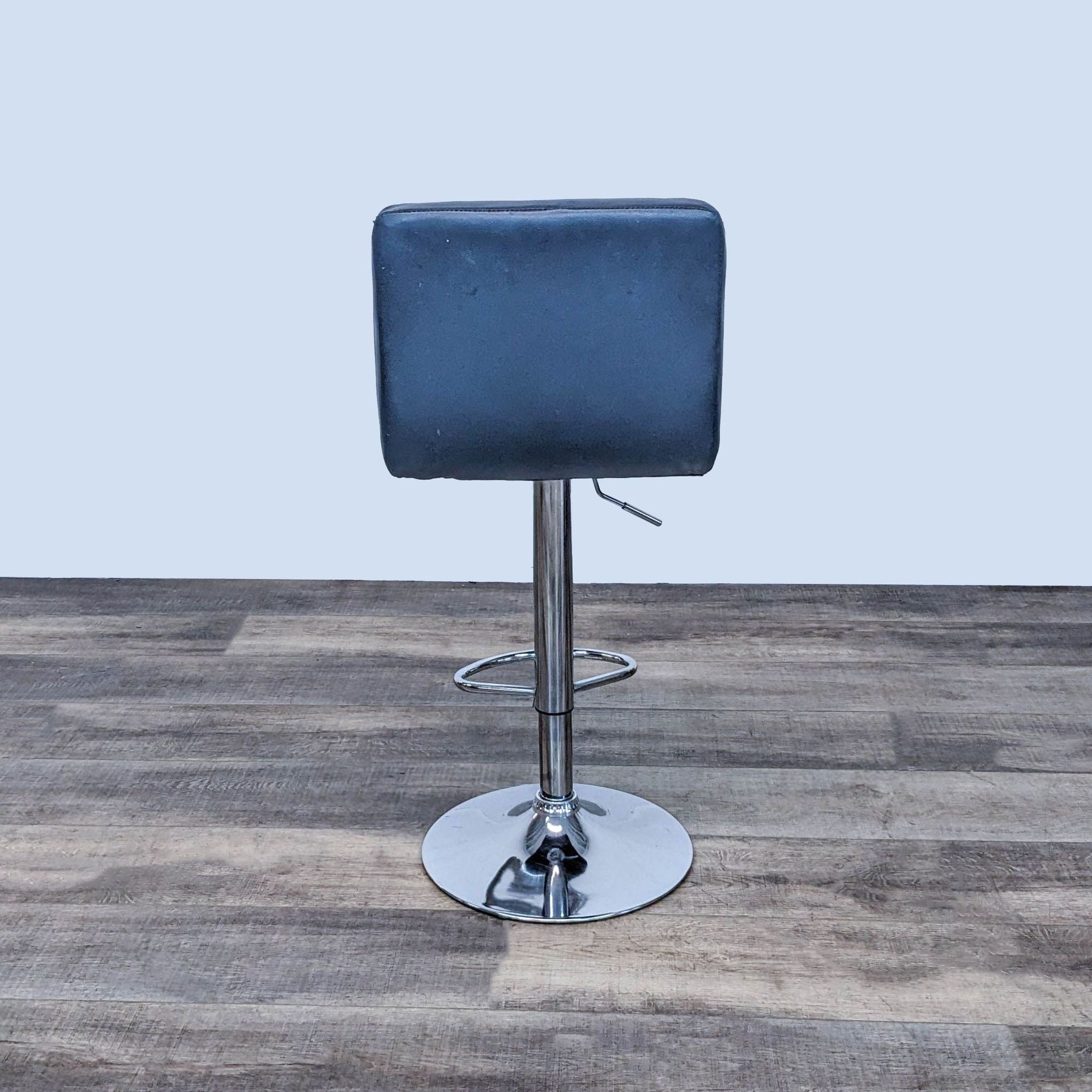Close-up of Reperch black padded stool showcasing the leather texture and stitching, with chrome base visible below.