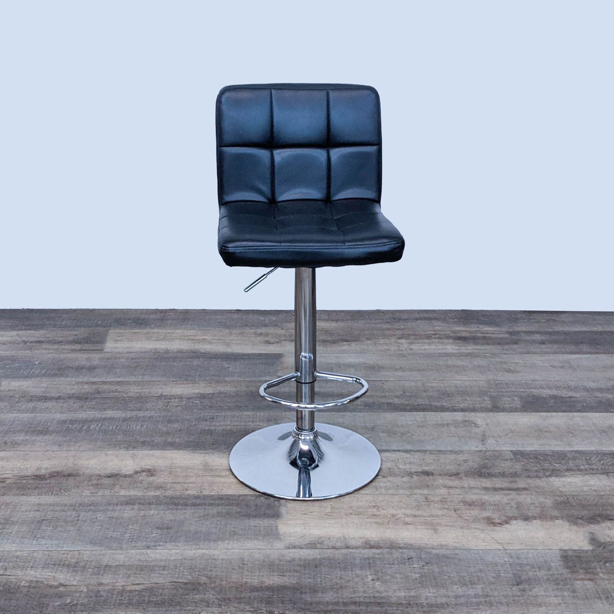 Reperch padded black leather-look stool with square seat and chrome gas lift frame, on wooden floor.