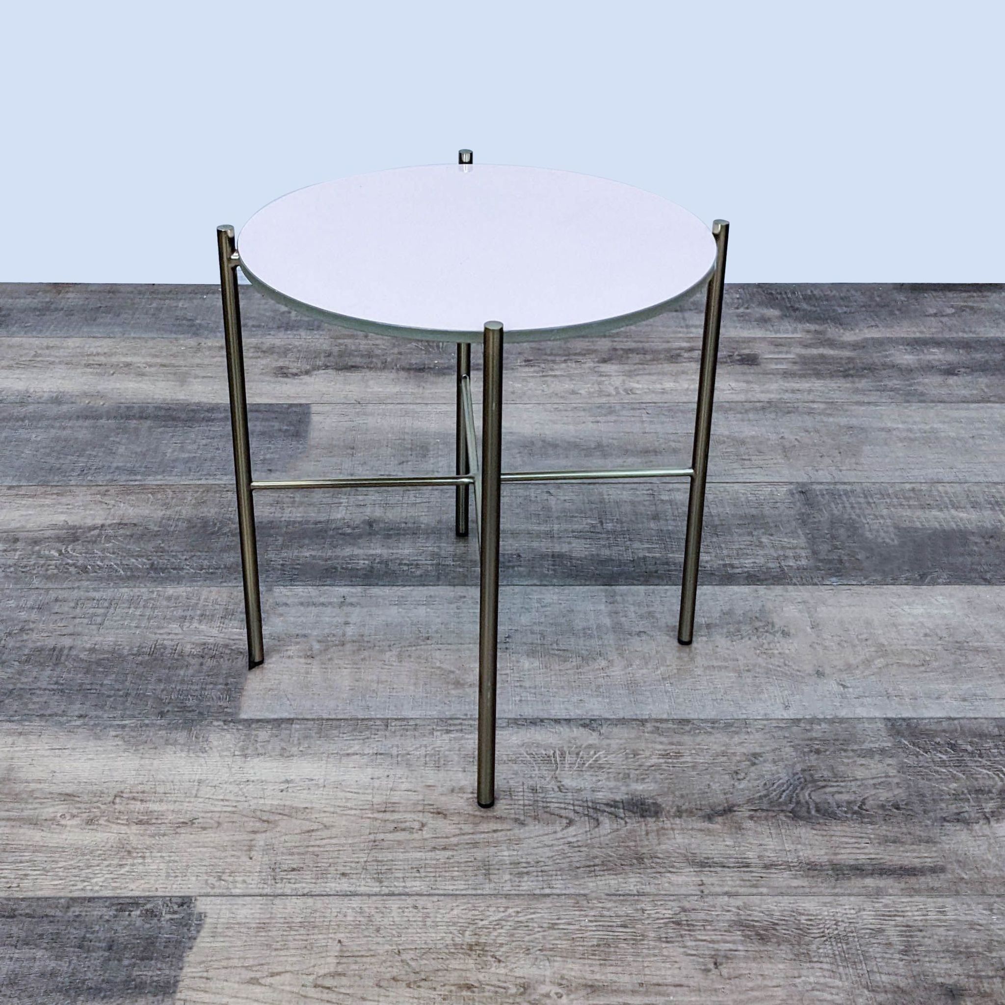 Reperch brand end table with a round opaque glass top on a three-legged metal base, set on a wooden floor.
