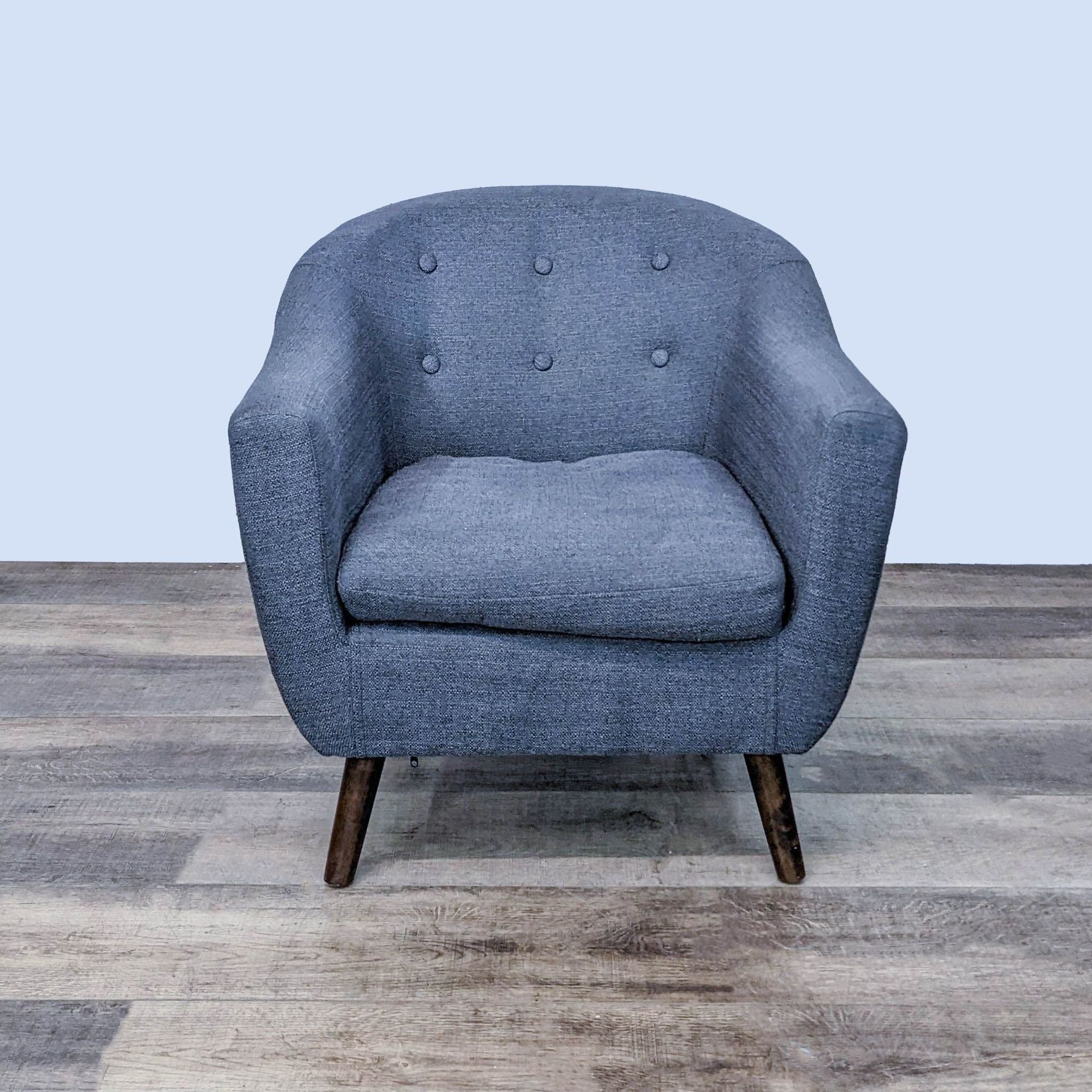 Mid-century style Reperch lounge armchair with tufted backrest and tapered legs, front view.