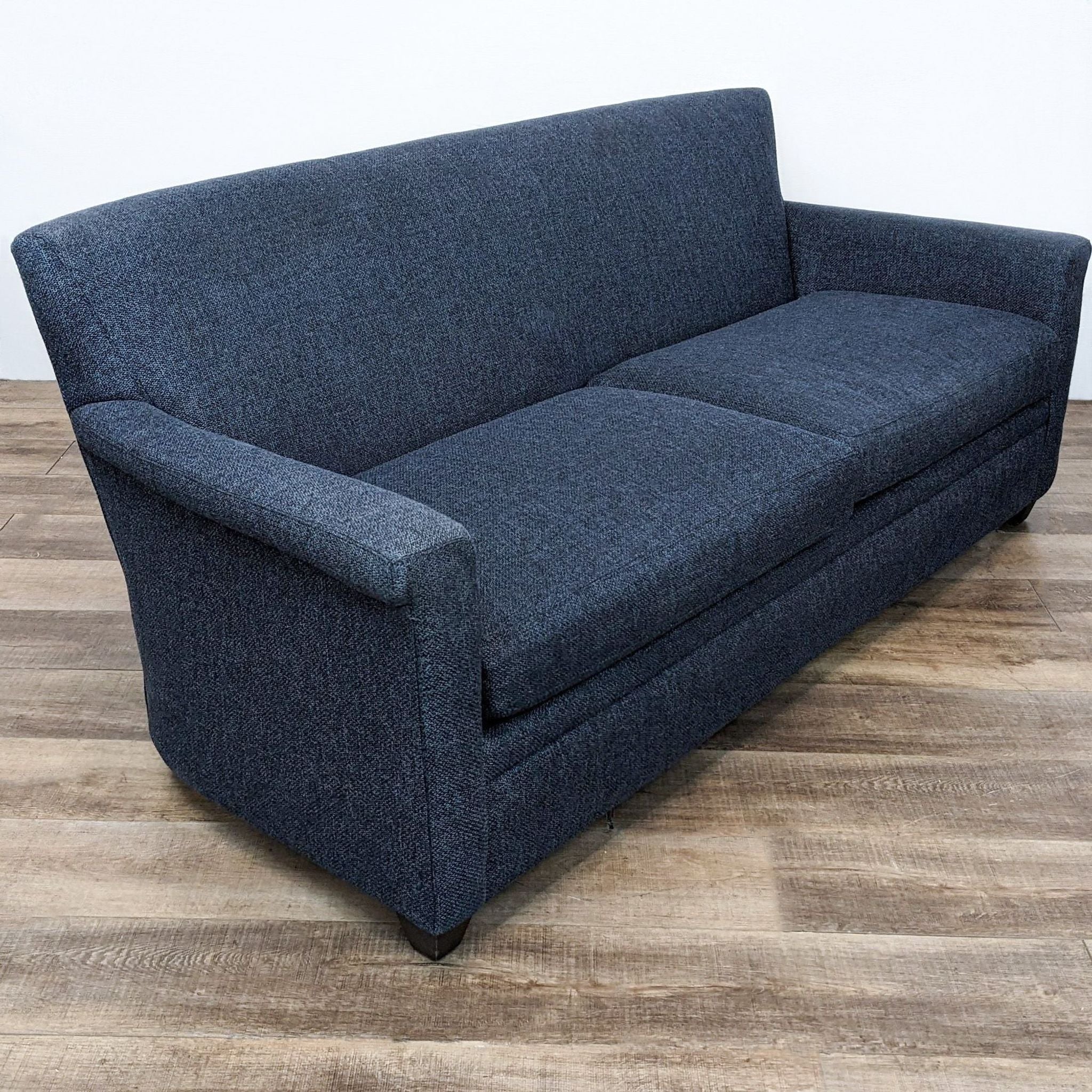 Compact Crate & Barrel dark gray loveseat with curved armrests and elegant dark wooden legs, suitable for small spaces.