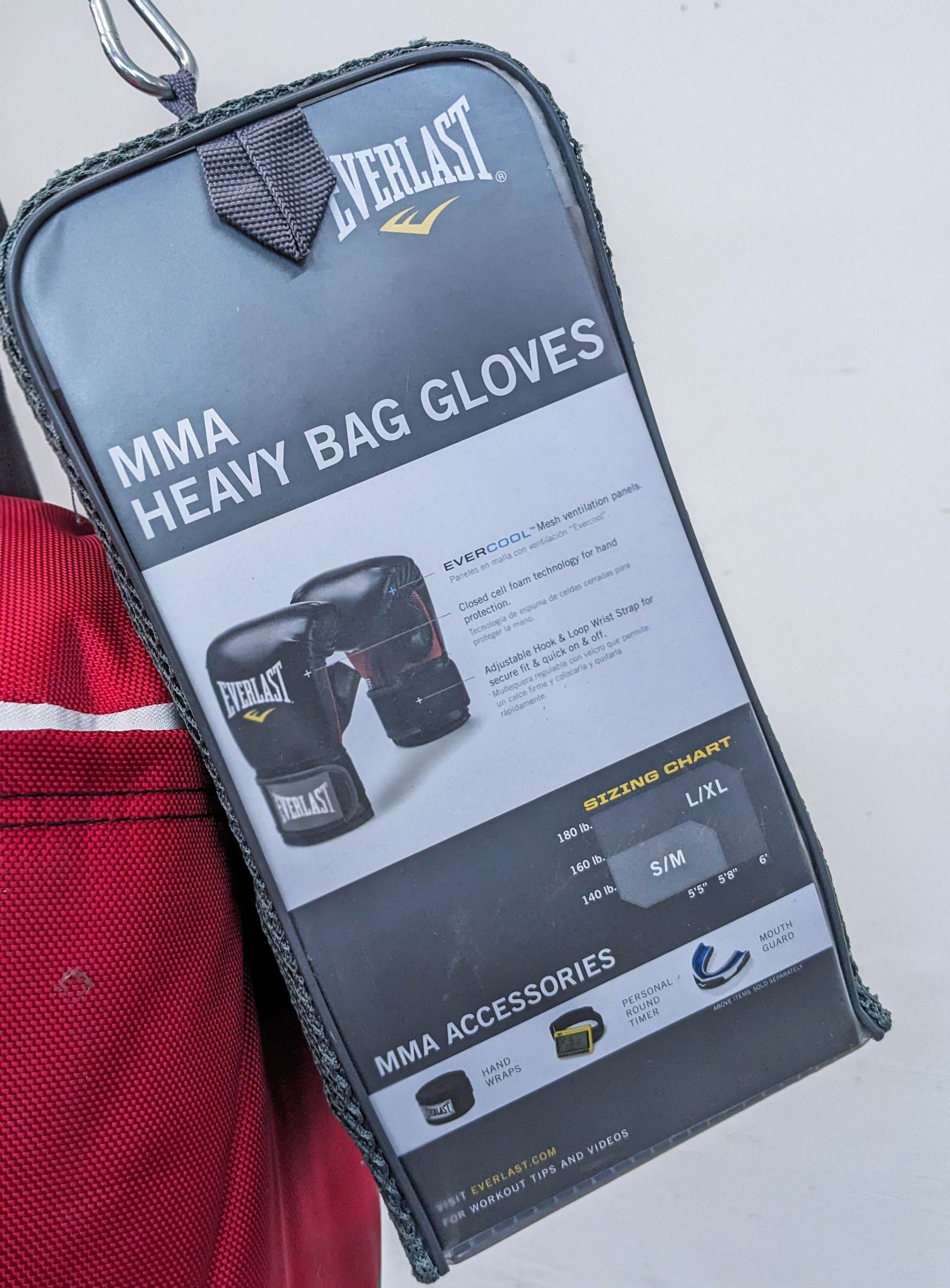 Everlast MMA heavy bag gloves packaging attached to a free-standing heavy bag, highlighting features and sizing chart for training gear.
