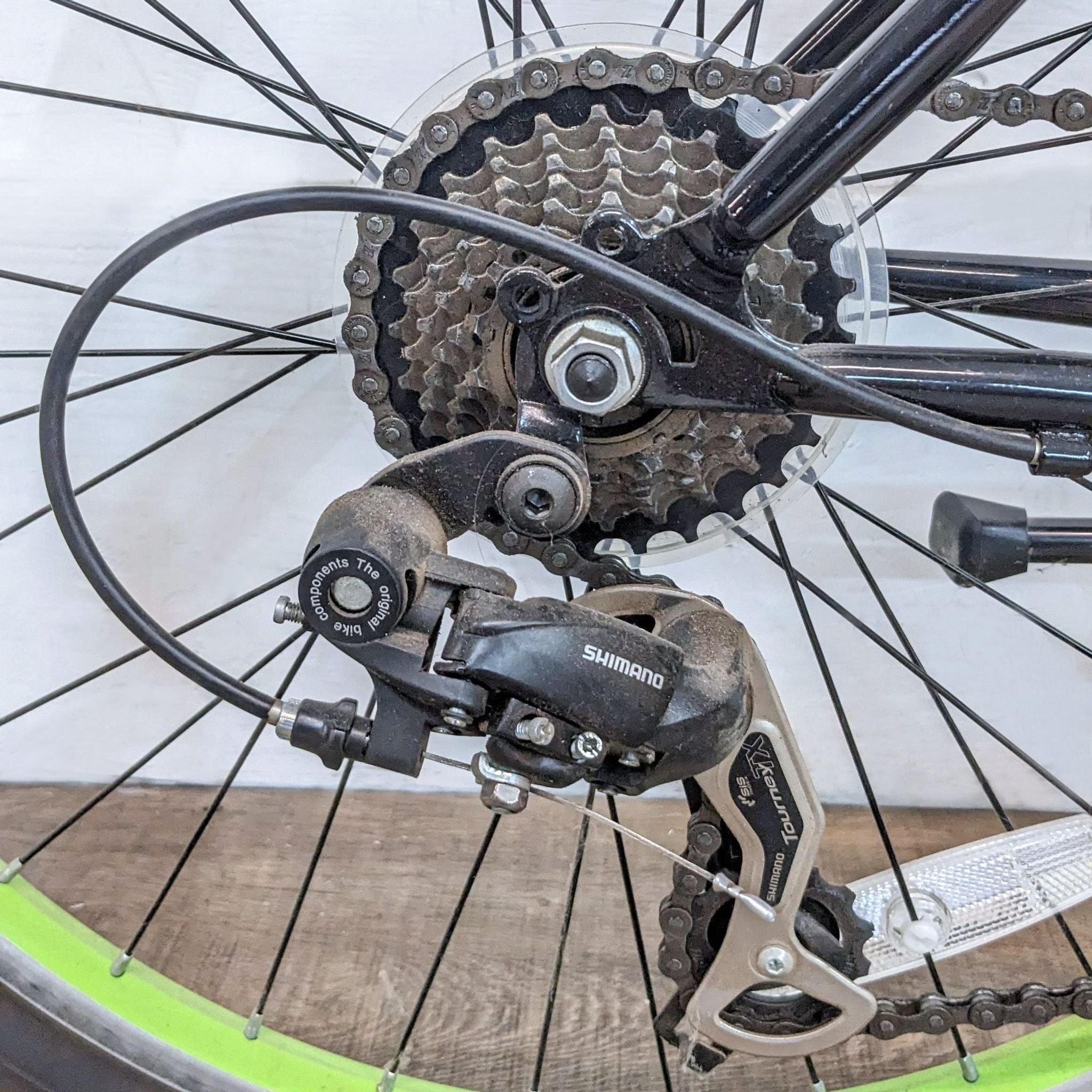 Close-up of a Schwinn bike's rear Shimano gear system and wheel showing the chain and cogs for changing gears.