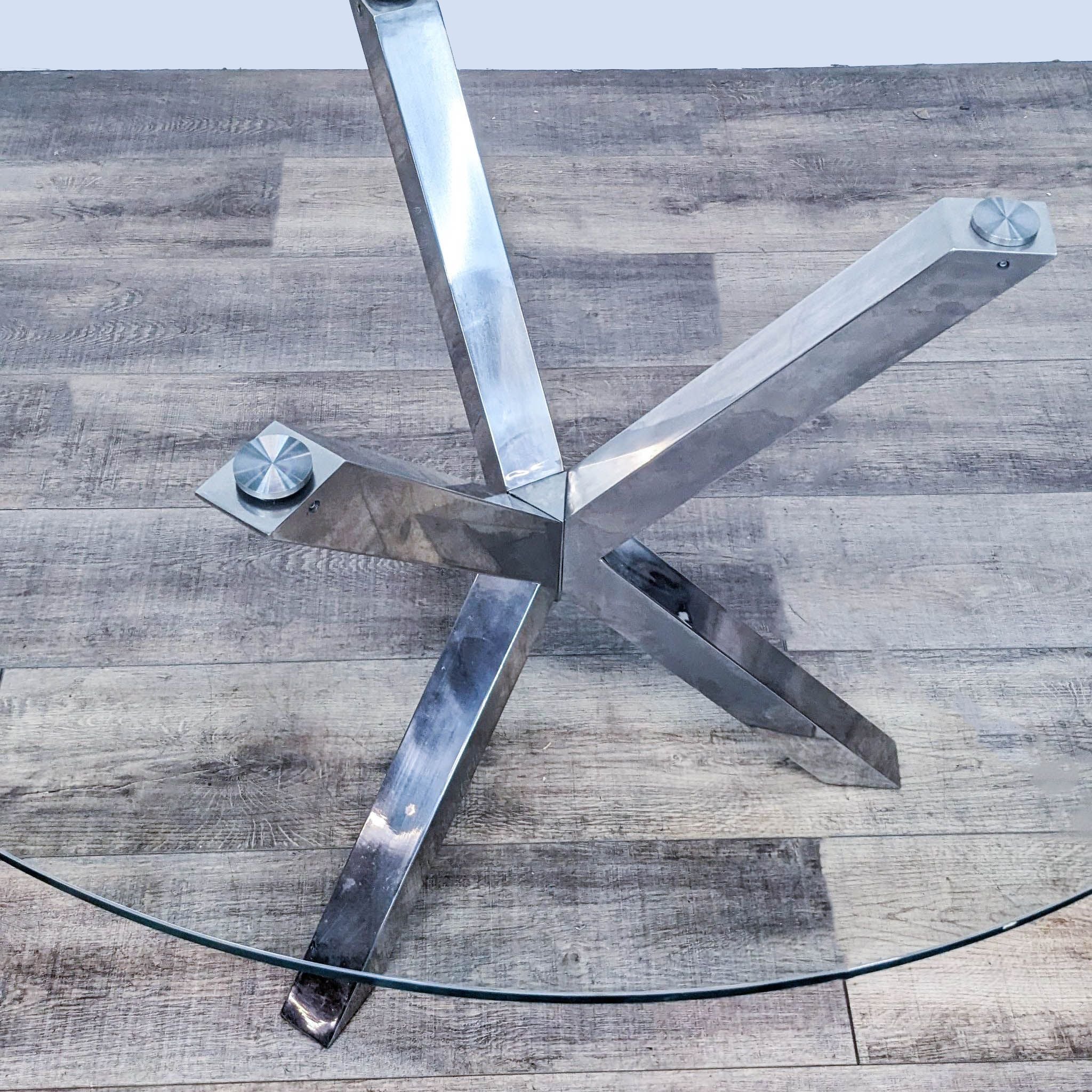 Top-down view of Wayfair's modern dining table showing the clear glass and chrome intersecting base.