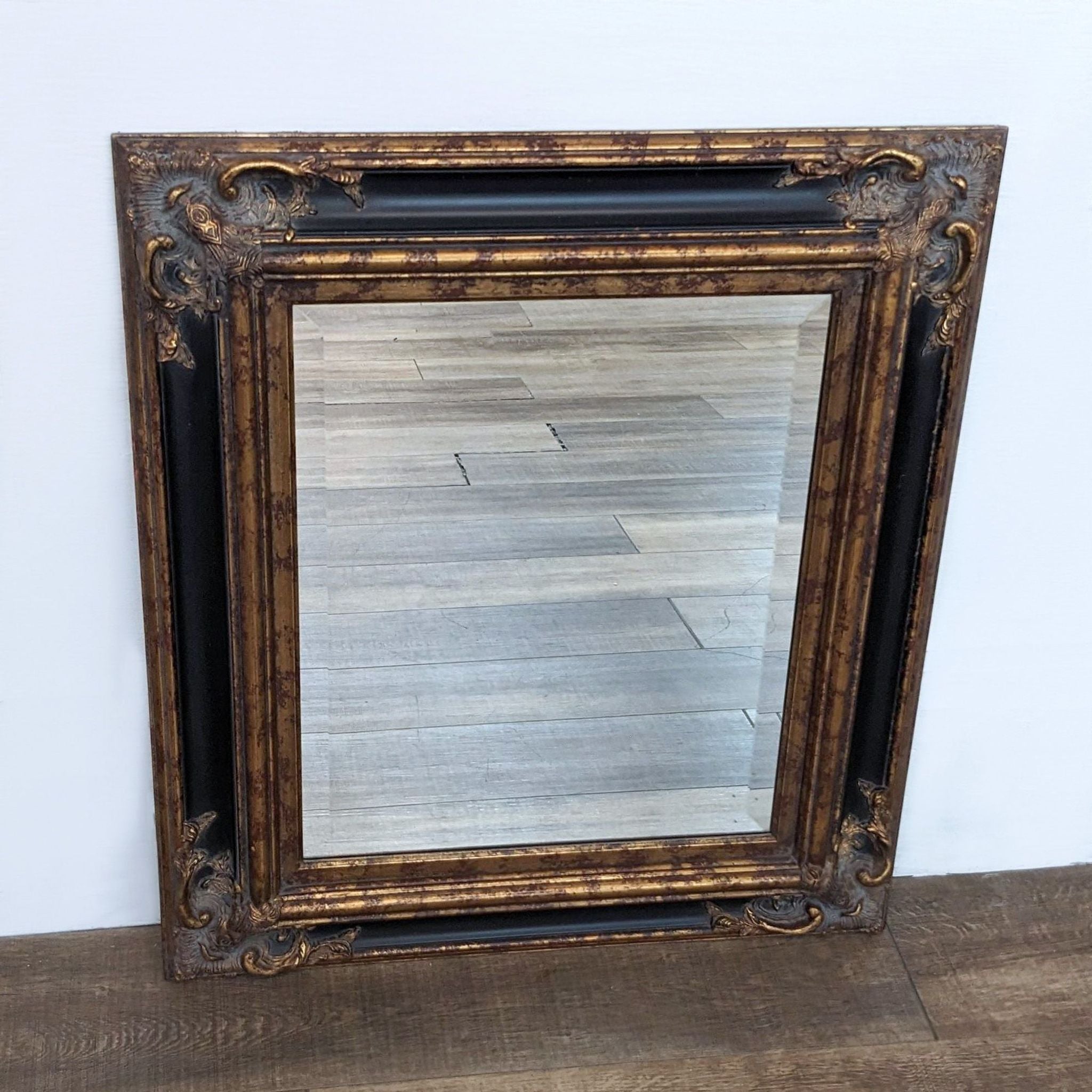 Vintage-style Baker Knapp and Tubbs framed wall mirror with detailed corners on a wooden floor.