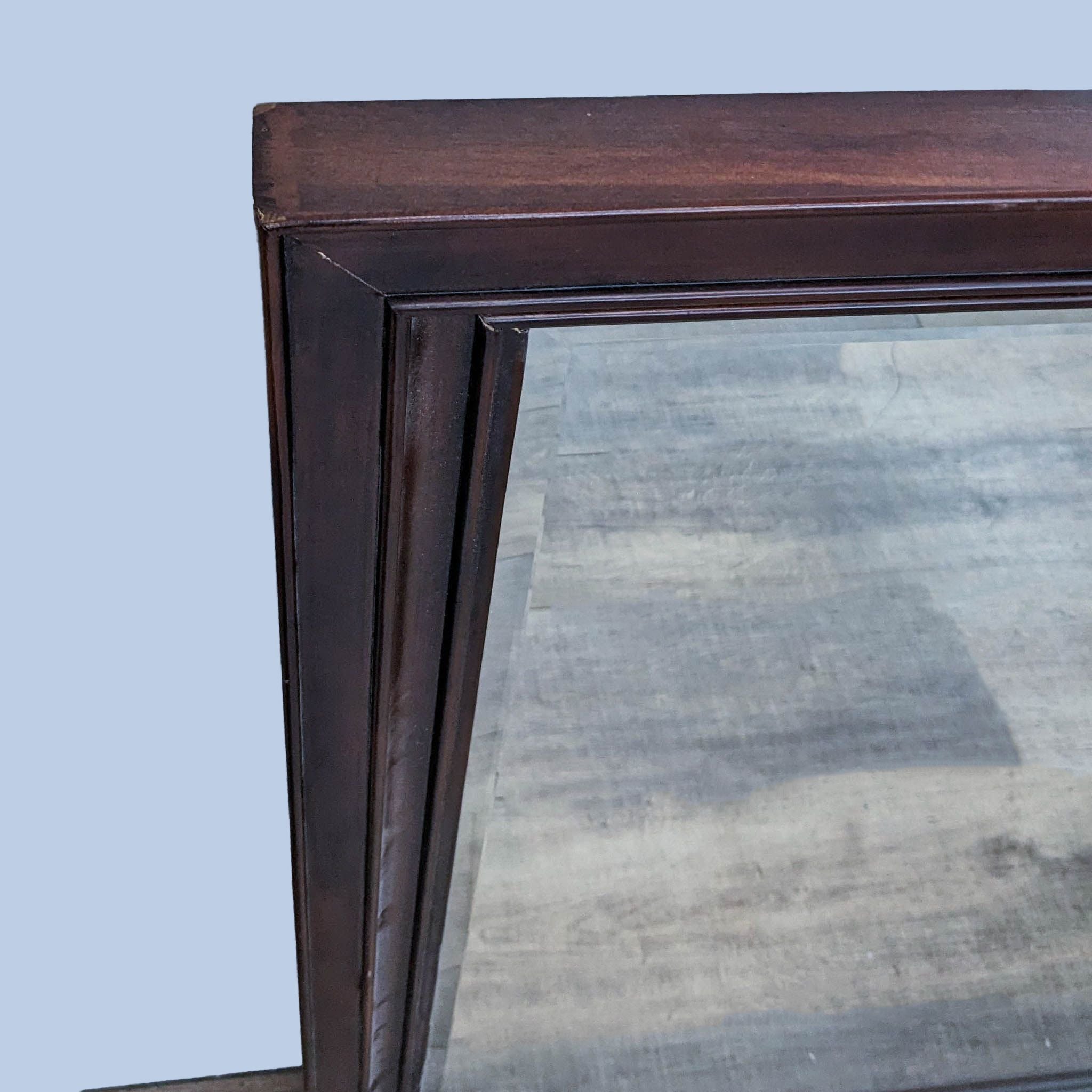Close-up of Reperch mirror's corner, showcasing the classic wood frame's beveled design and rich finish.