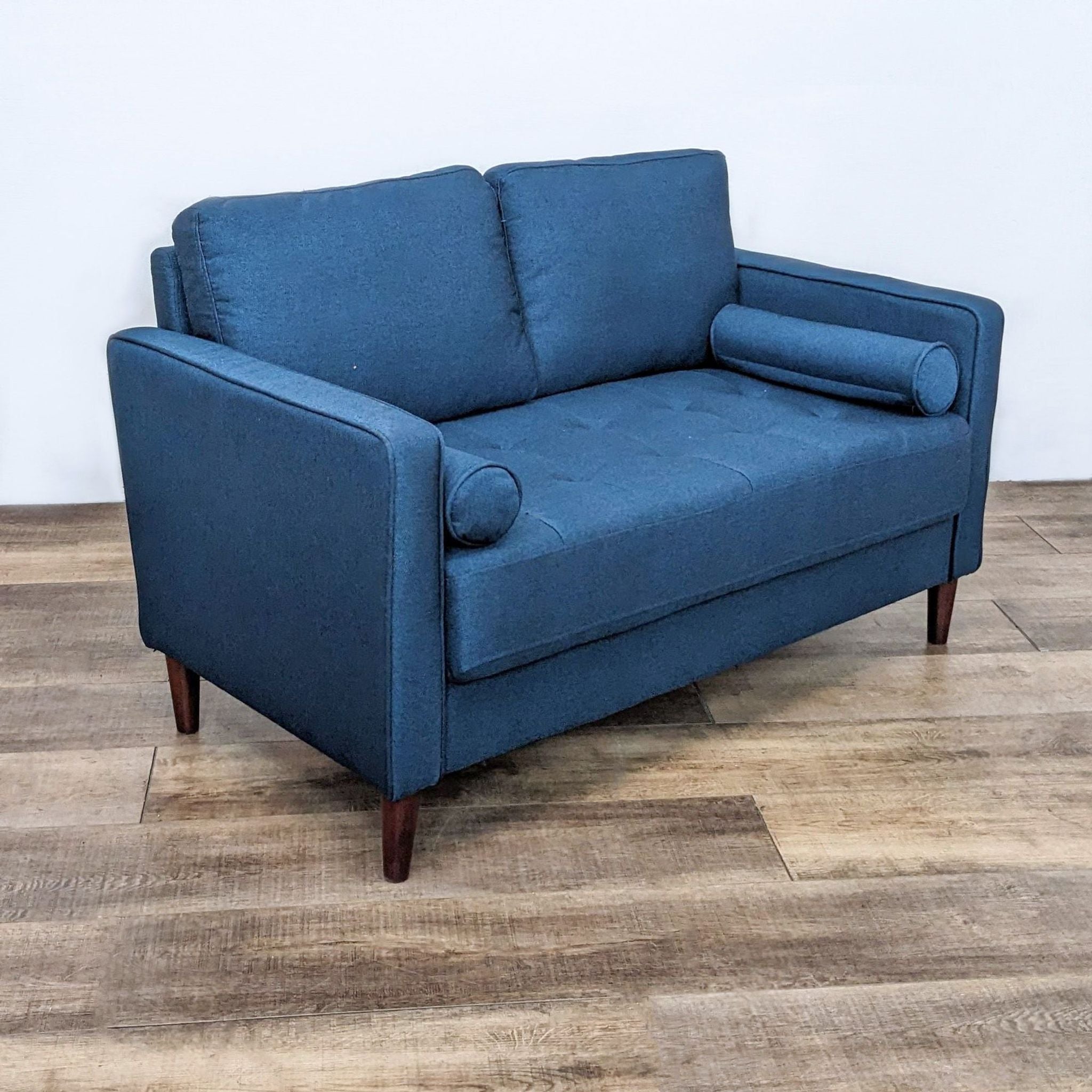 Alt text 2: Frontal view of a blue tufted loveseat with narrow arms and dark wooden feet, featuring Lifestyle Solutions tag.