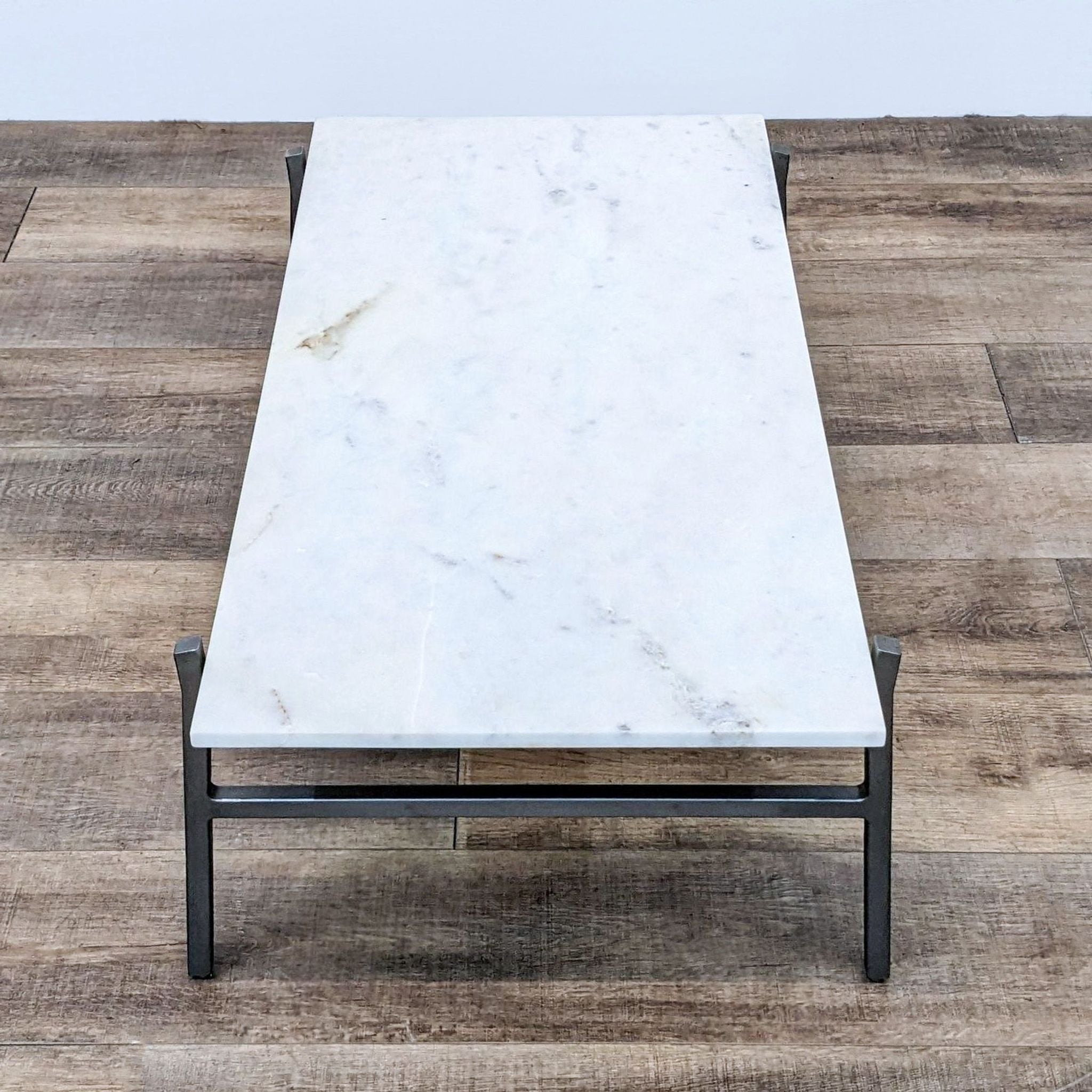 Rectangular marble top coffee table with a minimalist steel base by CB2, presented in a frontal view.