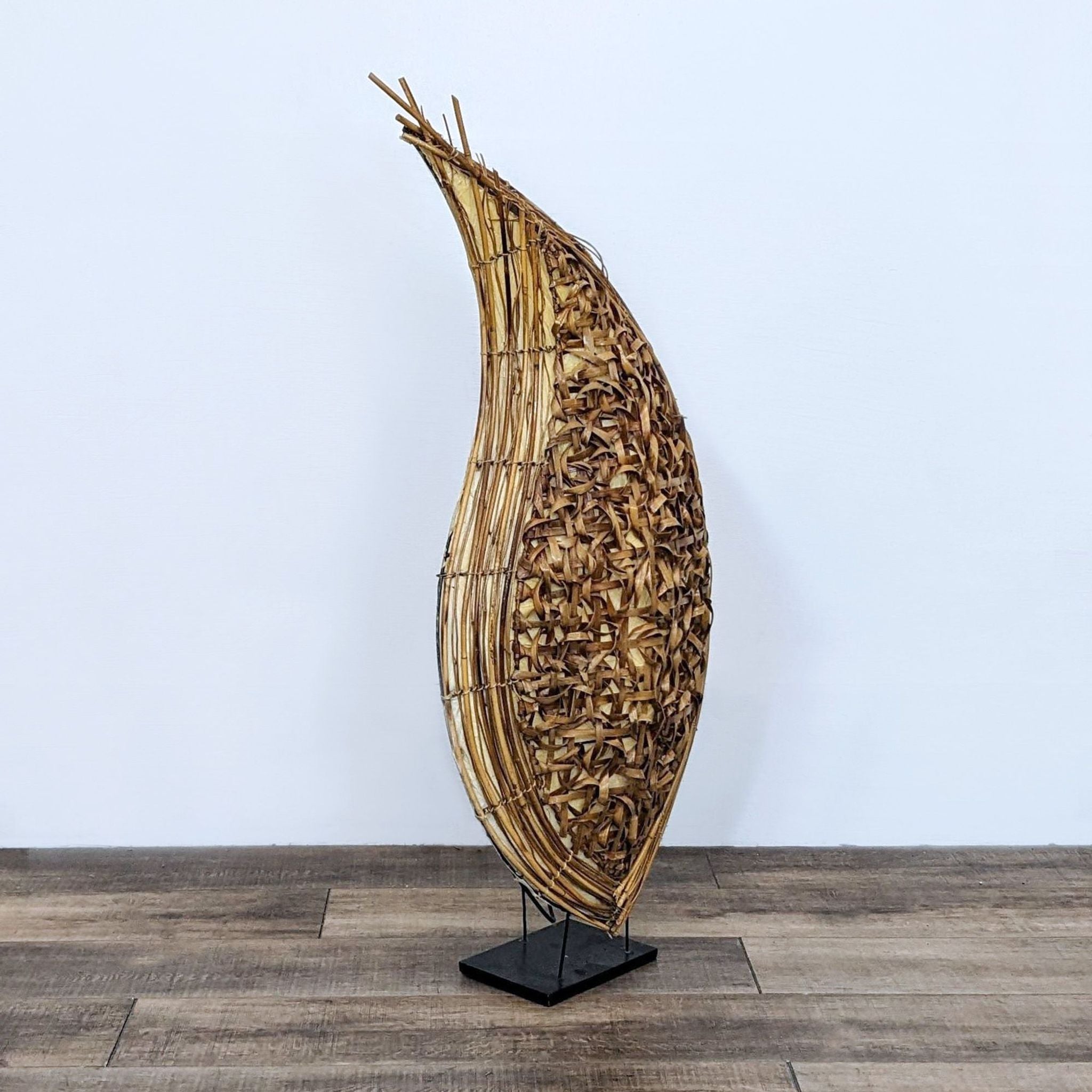 Abstract teardrop-shaped lighted sculpture by Reperch, crafted with natural woven materials on a black stand.