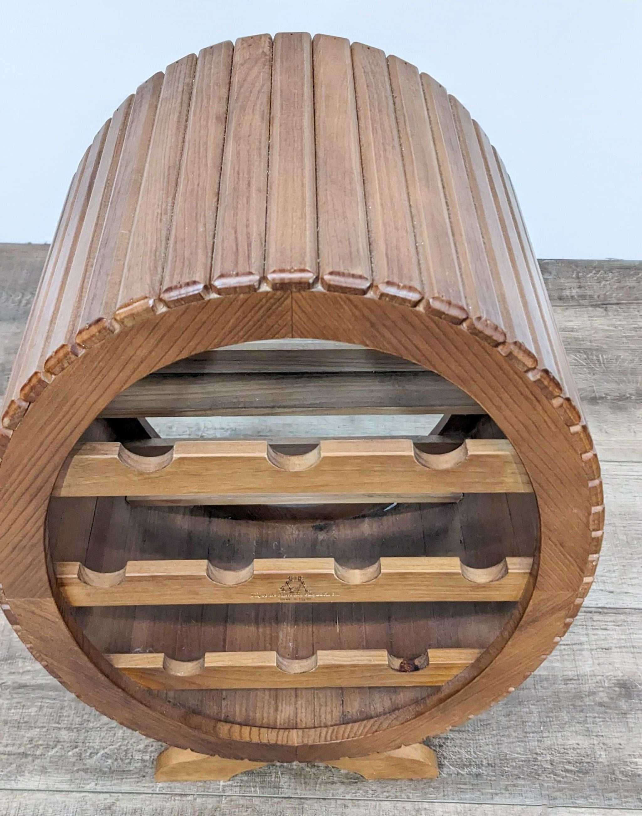 Alt text 3: Side view of a wooden barrel wine rack by Repech, showcasing its curved design and spaces for wine bottle storage.