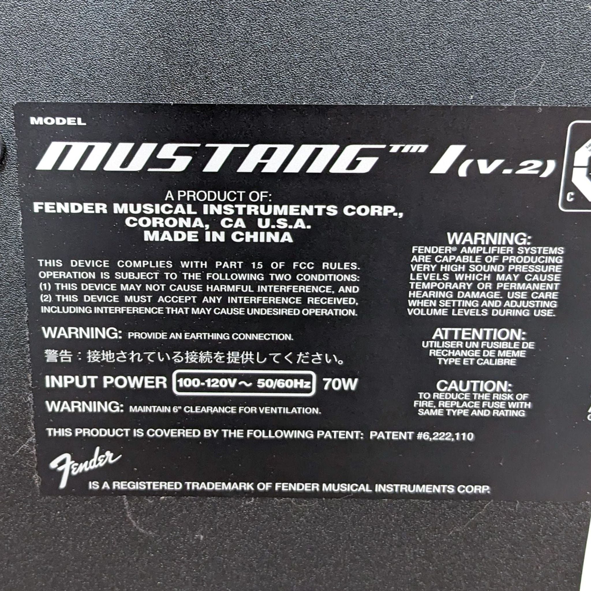 Close-up of a Fender Mustang guitar amplifier detail label indicating model, power specifications, warnings, and branding.
