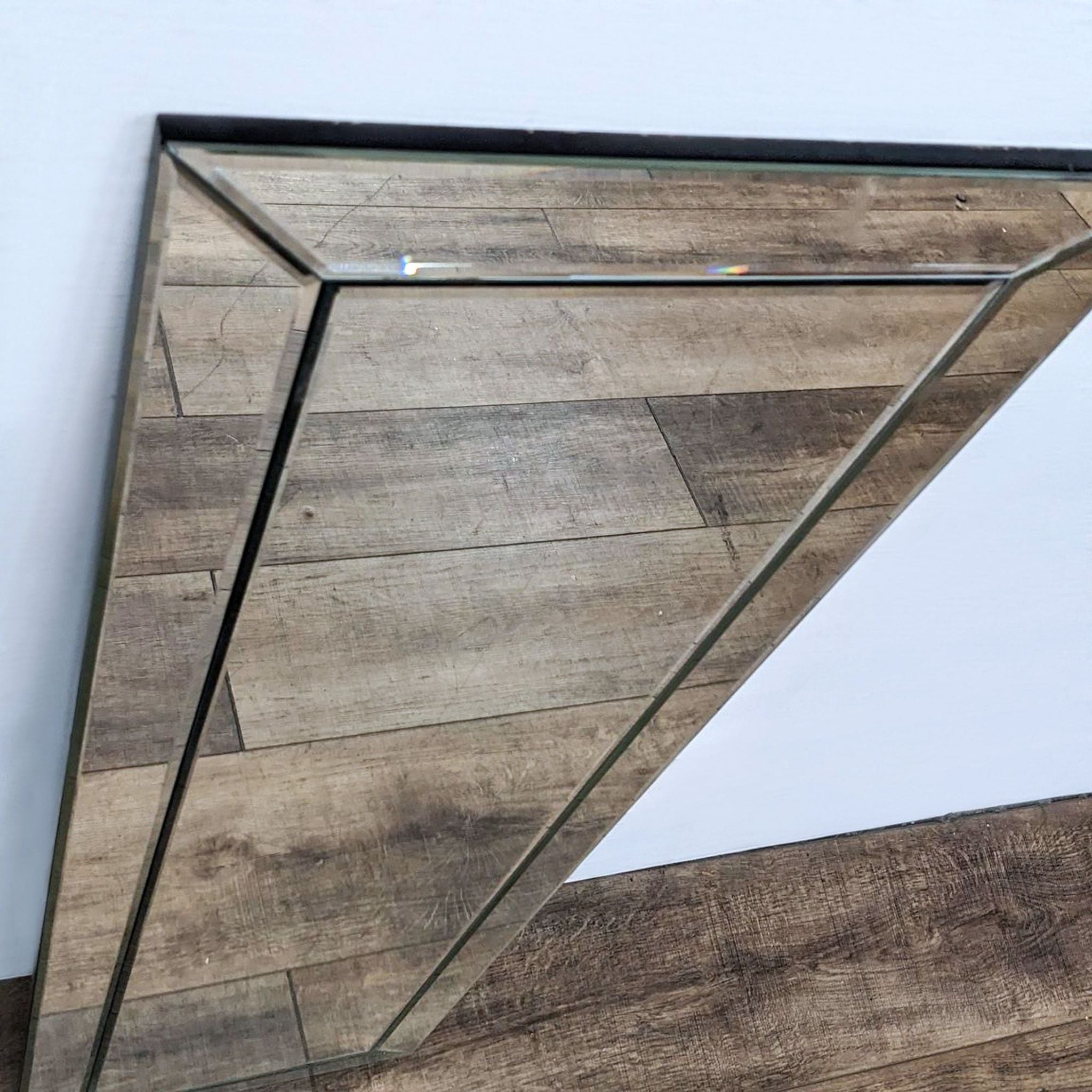 Close-up of Reperch mirror's beveled frame detail, highlighting the triangular mirror design.