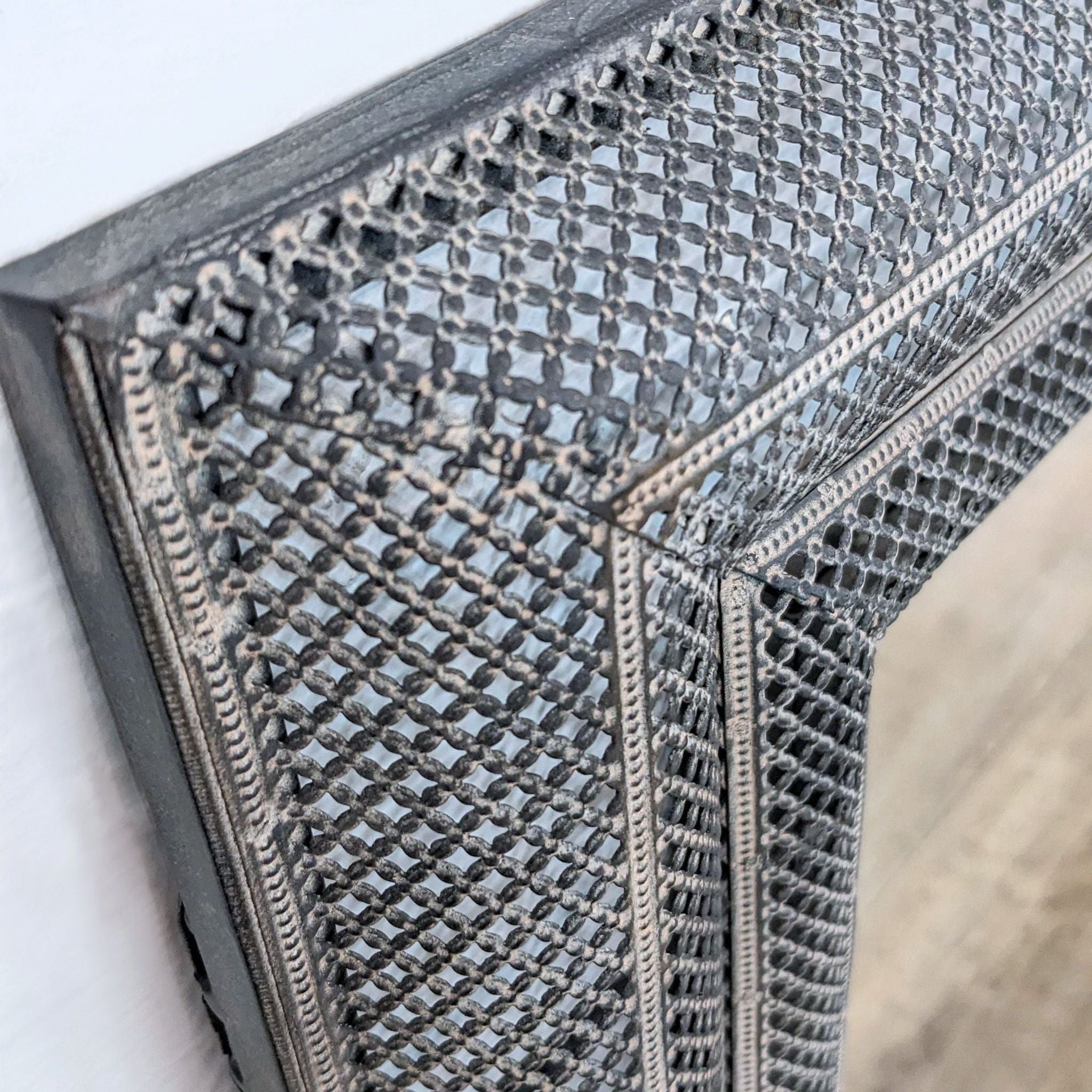 Close-up of an Uttermost mirror's textured frame with a stylish geometric pattern, enhancing home decor.