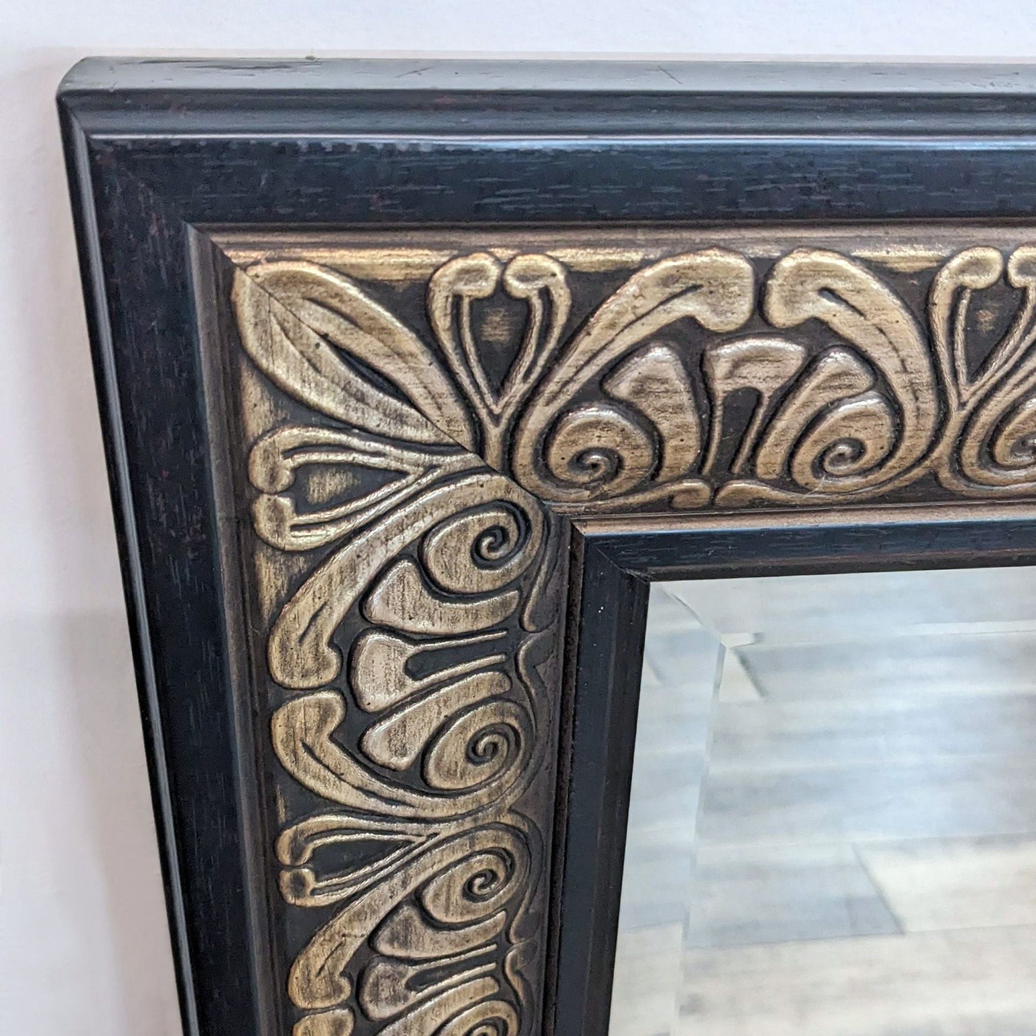 2. Close-up of World Market mirror's ornate carved detailing in antique brass finish, showcasing intricate patterns on its dark frame.